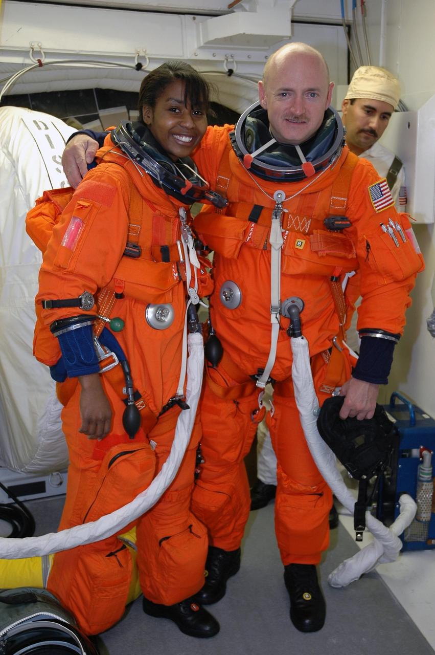 KENNEDY SPACE CENTER, FLA. - In the White Room on Launch Pad 39B, STS-121 Mission Specialist Stephanie Wilson and Pilot Mark Kelly pause for a photo opportunity before making final adjustments to their launch suits before entering Space Shuttle Discovery. The crew is taking part in a full dress rehearsal for launch, including countdown and culminating in main engine cutoff. The rehearsal is the final part of Terminal Countdown Demonstration Test (TCDT) activities that the crew has been involved in for two days. TCDT provides the crew of each mission an opportunity to participate in various simulated countdown activities, including equipment familiarization and emergency egress training. Mission STS-121 is scheduled to be launched July 1. Photo credit: NASA/Amanda Diller