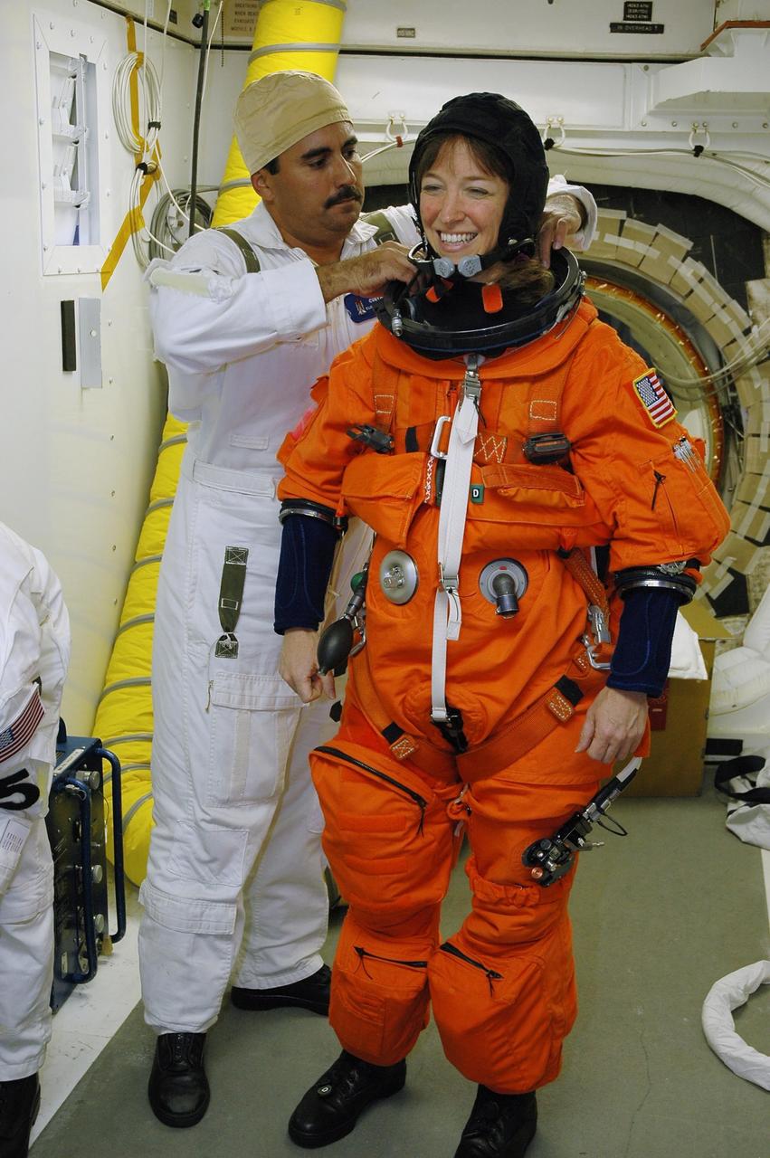 KENNEDY SPACE CENTER, FLA. - In the White Room on Launch Pad 39B, STS-121 Mission Specialist Lisa Nowak has her launch suit checked by a member of the closeout crew before she enters Space Shuttle Discovery. The crew is taking part in a full dress rehearsal for launch, including countdown and culminating in main engine cutoff. The rehearsal is the final part of Terminal Countdown Demonstration Test (TCDT) activities that the crew has been involved in for two days. TCDT provides the crew of each mission an opportunity to participate in various simulated countdown activities, including equipment familiarization and emergency egress training. Mission STS-121 is scheduled to be launched July 1. Photo credit: NASA/Amanda Diller