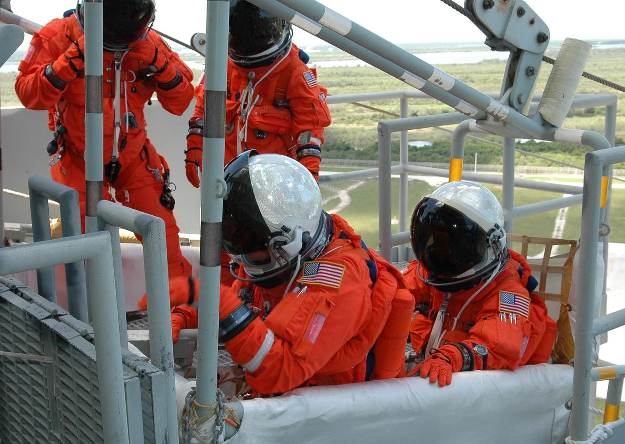 KENNEDY SPACE CENTER, FLA. - STS-121 crew members wait to climb into the slidewire basket on Launch Pad 39B. They are taking part in emergency egress practice, part of the Terminal Countdown Demonstration Test (TCDT) activities that include a simulated countdown culminating in main engine cutoff. Mission STS-121 is scheduled to be launched July 1. Photo credit: NASA/Kim Shiflett