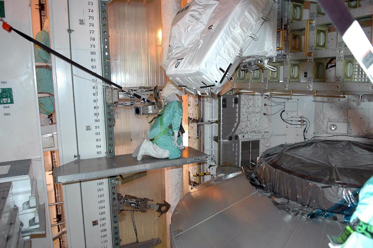 KENNEDY SPACE CENTER, FLA. - Inside the payload changeout room on Launch Pad 39B, STS-121 Mission Specialist Piers Sellers looks closely at payload elements installed on the integrated cargo carrier. He is dressed in a clean room suit, appropriate for the environmentally clean or "white room" condition in which the payload resides before being transferred to the shuttle's payload bay. At lower right is the multi-purpose logistics module Leonardo, which is carrying supplies and equipment for the International Space Station. The payload also includes the lightweight multi-purpose experiment support structure carrier. Crew members are at NASA's Kennedy Space Center for Terminal Countdown Demonstration Test activities, which include equipment familiarization and a simulated launch countdown. Mission STS-121 is scheduled for launch on Space Shuttle Discovery on July 1. Photo credit: NASA/Kim Shiflett