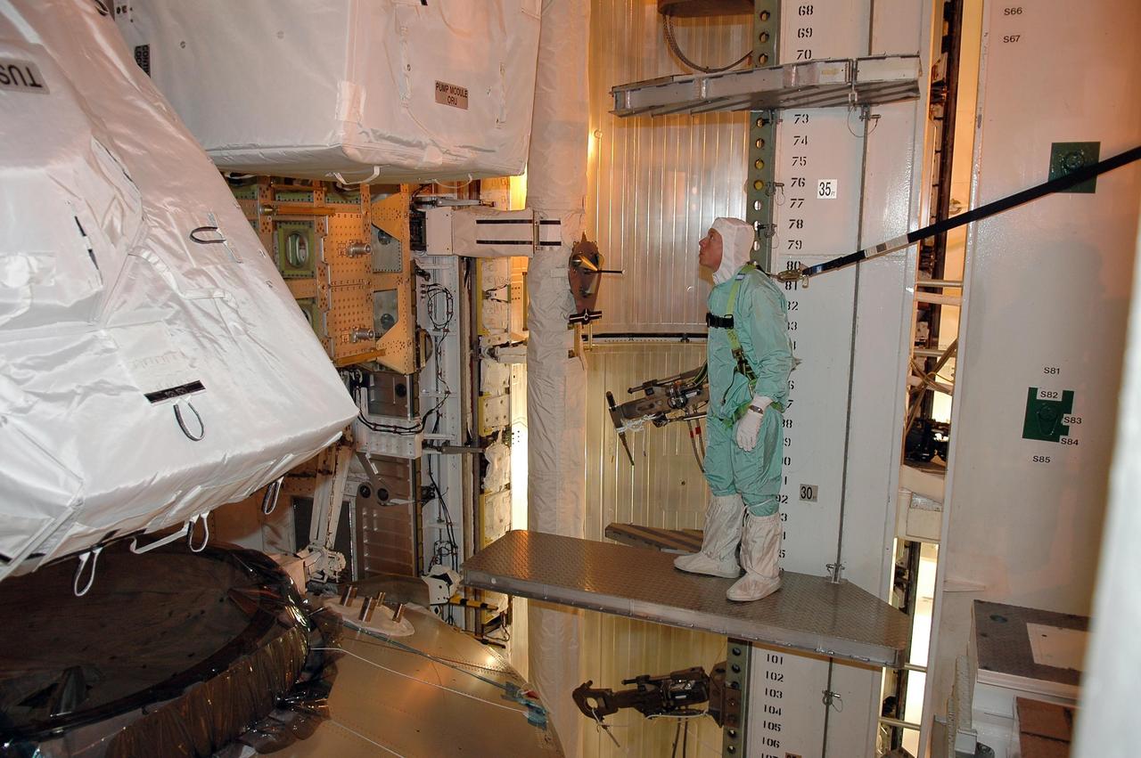 KENNEDY SPACE CENTER, FLA. - Inside the payload changeout room on Launch Pad 39B, STS-121 Mission Specialist Michael Fossum looks closely at part of the payload for the mission. He is dressed in a clean room suit, appropriate for the environmentally clean or "white room" condition in which the payload resides before being transferred to the shuttle's payload bay. At lower left is the multi-purpose logistics module Leonardo, which is carrying supplies and equipment for the International Space Station. The payload also includes the lightweight multi-purpose experiment support structure carrier and the integrated cargo carrier. Crew members are at NASA's Kennedy Space Center for Terminal Countdown Demonstration Test activities, which include equipment familiarization and a simulated launch countdown. Mission STS-121 is scheduled for launch on Space Shuttle Discovery on July 1. Photo credit: NASA/Kim Shiflett