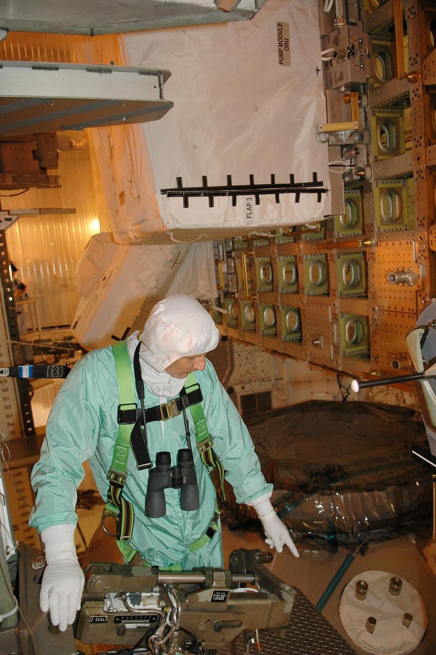 KENNEDY SPACE CENTER, FLA. - Inside the payload changeout room on Launch Pad 39B, STS-121 Mission Specialist Piers Sellers takes a close look at part of the payload for the mission. He is dressed in a clean room suit, appropriate for the environmentally clean or "white room" condition in which the payload resides before being transferred to the shuttle's payload bay. The payload includes the multi-purpose logistics module Leonardo, which is carrying supplies and equipment for the International Space Station, the lightweight multi-purpose experiment support structure carrier and the integrated cargo carrier. Crew members are at NASA's Kennedy Space Center for Terminal Countdown Demonstration Test activities, which include equipment familiarization and a simulated launch countdown. Mission STS-121 is scheduled for launch on Space Shuttle Discovery on July 1. Photo credit: NASA/Kim Shiflett