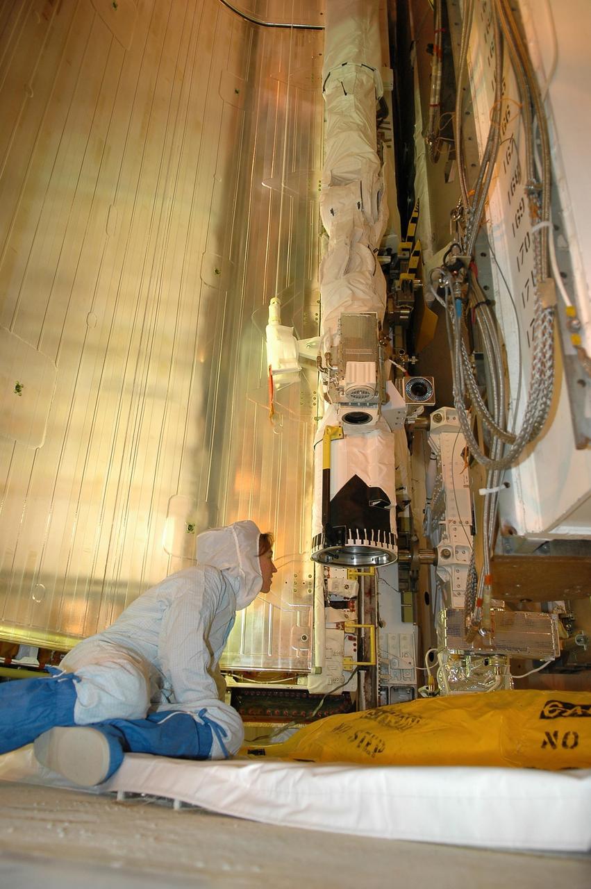 KENNEDY SPACE CENTER, FLA. - Inside the payload changeout room on Launch Pad 39B, STS-121 Mission Specialist Lisa Nowak takes a close look at part of the payload for the mission. She is dressed in a clean room suit, appropriate for the environmentally clean or "white room" condition in which the payload resides before being transferred to the shuttle's payload bay. The payload includes the multi-purpose logistics module Leonardo, which is carrying supplies and equipment for the International Space Station, the lightweight multi-purpose experiment support structure carrier and the integrated cargo carrier. Crew members are at NASA's Kennedy Space Center for Terminal Countdown Demonstration Test activities, which include equipment familiarization and a simulated launch countdown. Mission STS-121 is scheduled for launch on Space Shuttle Discovery on July 1. Photo credit: NASA/Kim Shiflett