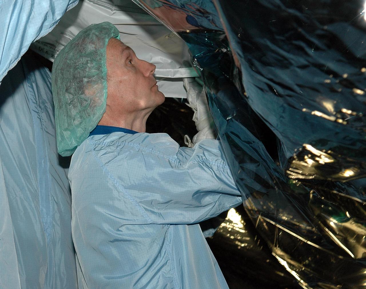 KENNEDY SPACE CENTER, FLA. - In the Space Station Processing Facility at NASA's Kennedy Space Center, STS-115 Mission Specialist Steve Maclean is installing a solar alpha rotary joint drive lock assembly multilayer installation cover. He and other crew members are at the center for Crew Equipment Interface Test activities. Equipment familiarization is a routine part of astronaut training and launch preparations. The mission will deliver the second port truss segment, the P3/P4 Truss, to attach to the first port truss segment, the P1 Truss, as well as deploy solar array set 2A and 4A. Launch on Space Shuttle Atlantis is scheduled for late August. Photo credit: NASA/Kim Shiflett