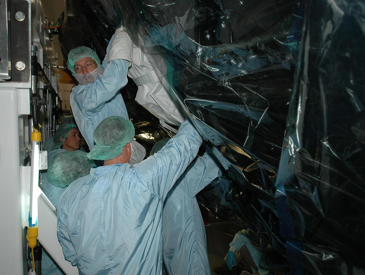 KENNEDY SPACE CENTER, FLA. -   In the Space Station Processing Facility at NASA's Kennedy Space Center, STS-115 Mission Specialist Joe Tanner is removing the P3 truss multiplexer-demultiplexer launch to activation multilayer installation blanket. He and other crew members are at the center for Crew Equipment Interface Test  activities. Equipment familiarization is a routine part of astronaut training and launch preparations.  The mission will deliver the second port truss segment, the P3/P4 Truss, to attach to the first port truss segment, the P1 Truss, as well as deploy solar array set 2A and 4A.  Launch on Space Shuttle Atlantis is scheduled for late August.  Photo credit: NASA/Kim Shiflett