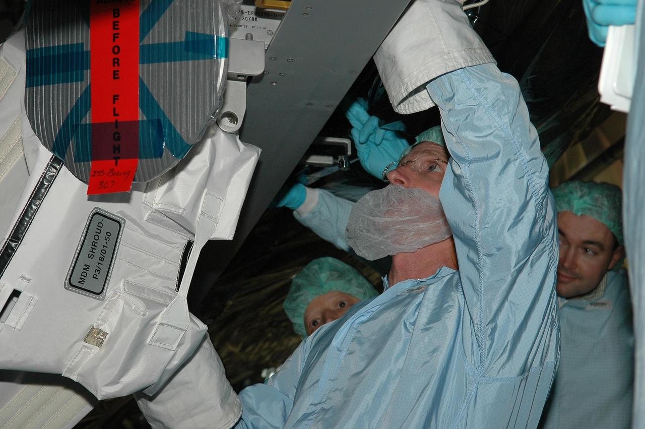 KENNEDY SPACE CENTER, FLA. -    In the Space Station Processing Facility at NASA's Kennedy Space Center, STS-115 Mission Specialist Joe Tanner is removing the P3 truss multiplexer-demultiplexer launch to activation multilayer installation blanket.  He and other crew members are at the center for Crew Equipment Interface Test  activities.  Equipment familiarization is a routine part of astronaut training and launch preparations.  The mission will deliver the second port truss segment, the P3/P4 Truss, to attach to the first port truss segment, the P1 Truss, as well as deploy solar array set 2A and 4A.  Launch on Space Shuttle Atlantis is scheduled for late August.  Photo credit: NASA/Kim Shiflett