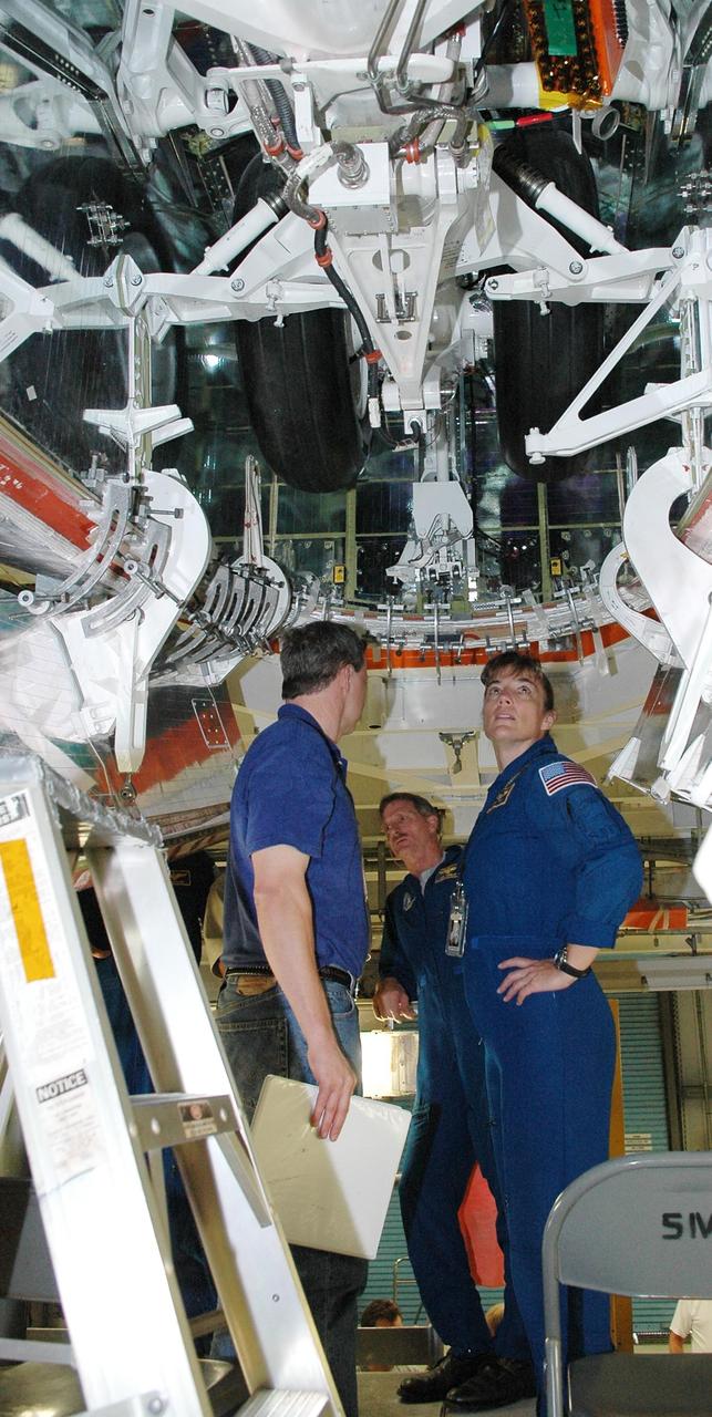 KENNEDY SPACE CENTER, FLA. -    In the Orbiter Processing Facility, STS-115 crew members examine the wheel well on the orbiter Atlantis, the designated launch vehicle for their mission. At center is Mission Specialist Joseph Tanner; at right is Mission Specialist Heidemarie Stefanyshyn-Piper. The crew is at the center for Crew Equipment Interface Test activities, which involves equipment familiarization,  a routine part of astronaut training and launch preparations.  The mission will deliver the second port truss segment, the P3/P4 Truss, to attach to the first port truss segment, the P1 Truss, as well as deploy solar array set 2A and 4A.  Launch on Space Shuttle Atlantis is scheduled for late August.  Photo credit: NASA/Kim Shiflett