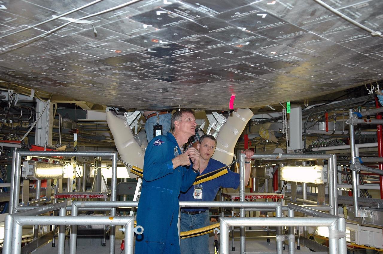 KENNEDY SPACE CENTER, FLA. -   In the Orbiter Processing Facility, STS-115 Mission Specialist Joseph Tanner (foreground) examines tiles on the orbiter Atlantis,  the designated launch vehicle for the mission.  The crew is at the center for Crew Equipment Interface Test activities, which involves equipment familiarization,  a routine part of astronaut training and launch preparations.  The mission will deliver the second port truss segment, the P3/P4 Truss, to attach to the first port truss segment, the P1 Truss, as well as deploy solar array set 2A and 4A.  Launch on Space Shuttle Atlantis is scheduled for late August.  Photo credit: NASA/Kim Shiflett