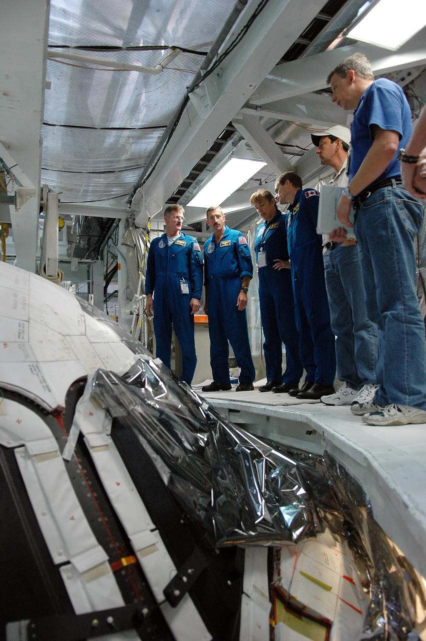 KENNEDY SPACE CENTER, FLA. - In the Orbiter Processing Facility, STS-115 crew members look over the cockpit on the orbiter Atlantis, the designated launch vehicle for their mission. From left are Mission Specialists Joseph Tanner, Daniel Burbank, Heidemarie Stefanyshyn-Piper and Steven MacLean, who represents the Canadian Space Agency. The crew is at the center for Crew Equipment Interface Test activities, which involves equipment familiarization, a routine part of astronaut training and launch preparations. The mission will deliver the second port truss segment, the P3/P4 Truss, to attach to the first port truss segment, the P1 Truss, as well as deploy solar array set 2A and 4A. Launch on Space Shuttle Atlantis is scheduled for late August. Photo credit: NASA/Kim Shiflett