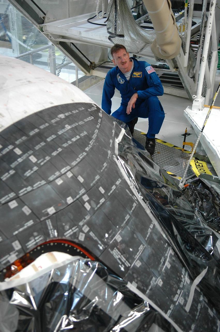 KENNEDY SPACE CENTER, FLA. - In the Orbiter Processing Facility, STS-115 Mission Specialist Joseph Tanner takes a closer look at the orbiter Atlantis, the designated launch vehicle for the mission  The crew is at the center for Crew Equipment Interface Test activities, which involves equipment familiarization,  a routine part of astronaut training and launch preparations.  The mission will deliver the second port truss segment, the P3/P4 Truss, to attach to the first port truss segment, the P1 Truss, as well as deploy solar array set 2A and 4A.  Launch on Space Shuttle Atlantis is scheduled for late August.  Photo credit: NASA/Kim Shiflett