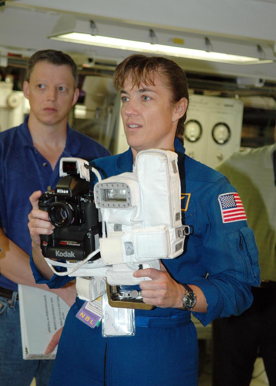 KENNEDY SPACE CENTER, FLA. - In the Orbiter Processing Facility, STS-115 Mission Specialist Heidemarie Stefanyshyn-Piper takes her turn at using a camera that is a mockup of one the crew will use to take photographs on-orbit.   The crew is at the center for Crew Equipment Interface Test activities, which involves equipment familiarization,  a routine part of astronaut training and launch preparations.  The mission will deliver the second port truss segment, the P3/P4 Truss, to attach to the first port truss segment, the P1 Truss, as well as deploy solar array set 2A and 4A.  Launch on Space Shuttle Atlantis is scheduled for late August.  Photo credit: NASA/Kim Shiflett