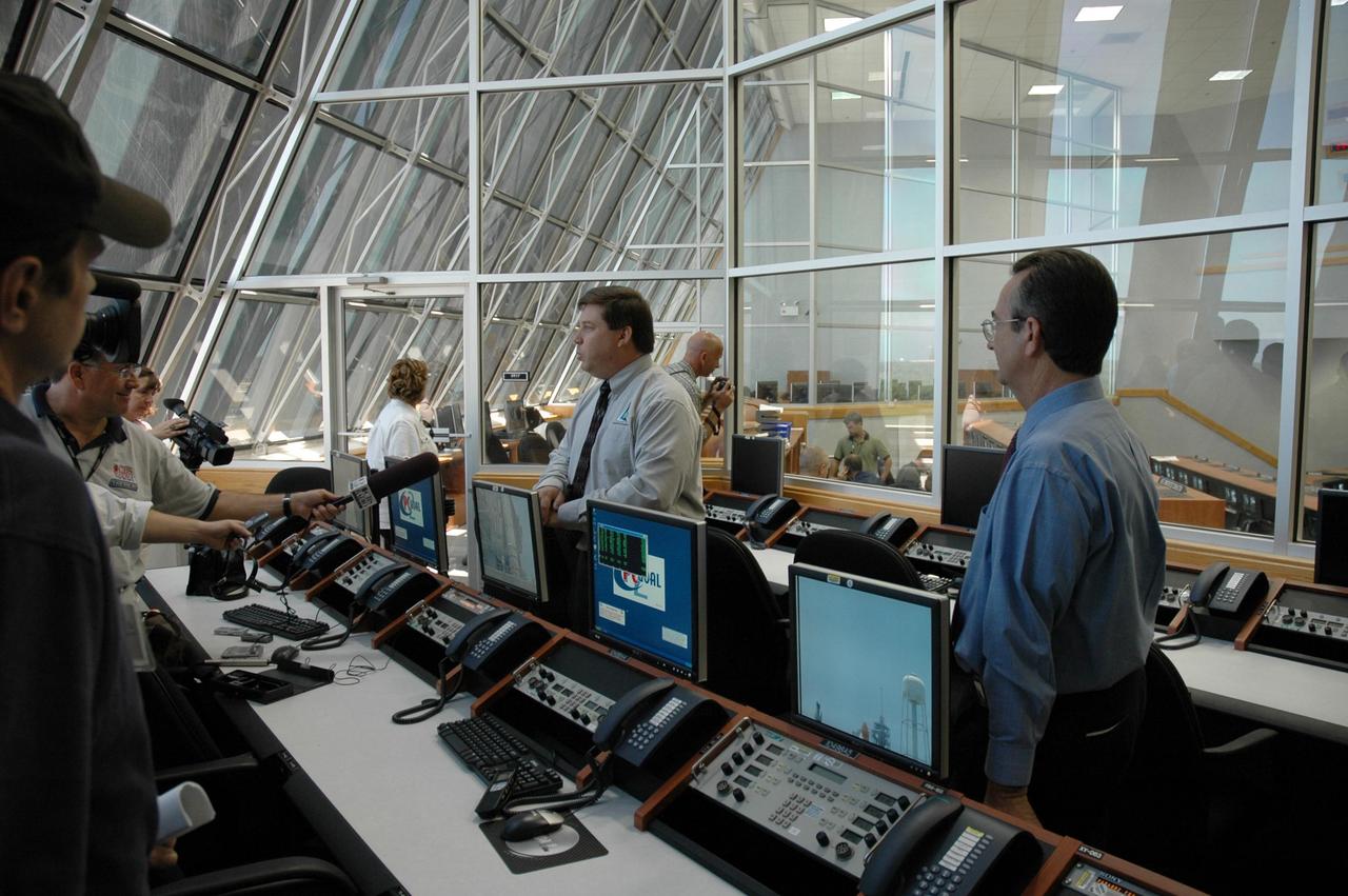 KENNEDY SPACE CENTER, FLA. - NASA Test Director Ted Mosteller (center) briefs the media about Firing Room 4 (FR4), which has been undergoing renovations for two years. FR4 is now designated the primary firing room for all remaining shuttle launches, and will also be used daily to manage operations in the Orbiter Processing Facilities and for integrated processing for the shuttle. The firing room now includes sound-suppressing walls and floors, new humidity control, fire-suppression systems and consoles, support tables with computer stations, communication systems and laptop computer ports. FR 4 also has power and computer network connections and a newly improved Checkout, Control and Monitor Subsystem. The renovation is part of the Launch Processing System Extended Survivability Project that began in 2003. United Space Alliance's Launch Processing System directorate managed the FR 4 project for NASA. Photo credit: NASA/Dimitri Gerondidakis