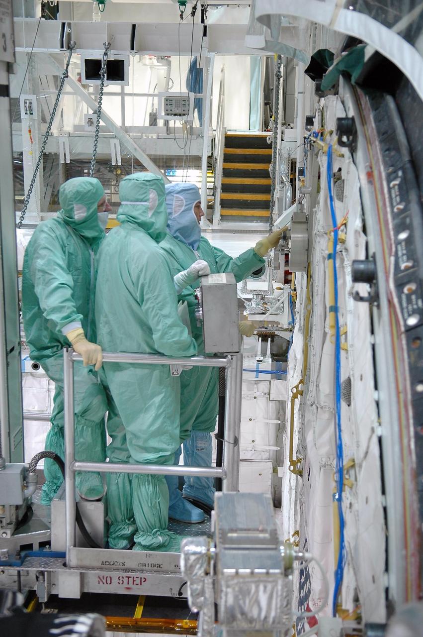 KENNEDY SPACE CENTER, FLA. -  In the Orbiter Processing Facility at NASA's Kennedy Space Center, STS-115 crew members inspect equipment in Atlantis's payload bay. Mission Specialists (at left) Joseph Tanner and (at right) Heidemarie Stefanyshyn-Piper look at the airlock.  The crew is at KSC for Crew Equipment Interface Test activities, which involves equipment familiarization,  a routine part of astronaut training and launch preparations.  The STS-115 mission will deliver the second port truss segment, the P3/P4 truss, to the International Space Station.  The crew will attach the P3 to the first port truss segment, the P1 truss, as well as deploy solar array set 2A and 4A.  Launch on Space Shuttle Atlantis is scheduled for late August. Photo credit: NASA/Kim Shiflett