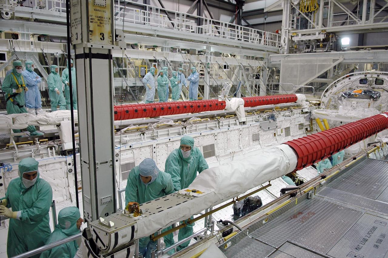 KENNEDY SPACE CENTER, FLA. -  In the Orbiter Processing Facility at NASA's Kennedy Space Center, STS-115 crew members inspect equipment in Atlantis's payload bay. At right are Mission Specialists Heidemarie Stefanyshyn-Piper and Joseph Tanner looking at the orbiter boom sensor system.   The crew is at KSC for Crew Equipment Interface Test activities, which involves equipment familiarization,  a routine part of astronaut training and launch preparations.  The STS-115 mission will deliver the second port truss segment, the P3/P4 truss, to the International Space Station.  The crew will attach the P3 to the first port truss segment, the P1 truss, as well as deploy solar array set 2A and 4A.  Launch on Space Shuttle Atlantis is scheduled for late August. Photo credit: NASA/Kim Shiflett