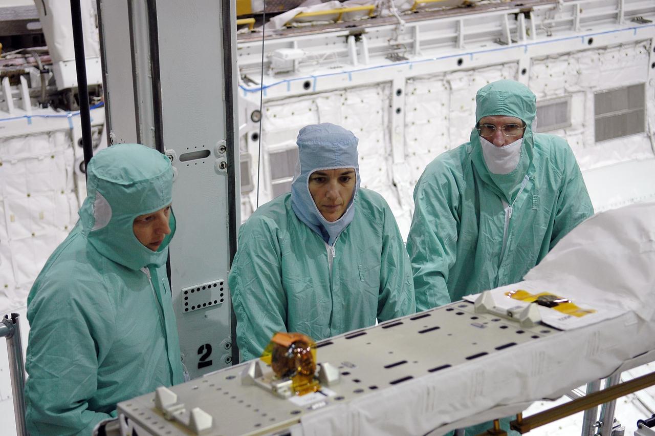 KENNEDY SPACE CENTER, FLA. -  In the Orbiter Processing Facility at NASA's Kennedy Space Center, STS-115 crew members inspect equipment in Atlantis's payload bay. Mission Specialists Heidemarie Stefanyshyn-Piper (center) and Joseph Tanner (right) look at the orbiter boom sensor system.  The crew is at KSC for Crew Equipment Interface Test activities, which involves equipment familiarization,  a routine part of astronaut training and launch preparations.  The STS-115 mission will deliver the second port truss segment, the P3/P4 truss, to the International Space Station.  The crew will attach the P3 to the first port truss segment, the P1 truss, as well as deploy solar array set 2A and 4A.  Launch on Space Shuttle Atlantis is scheduled for late August. Photo credit: NASA/Kim Shiflett