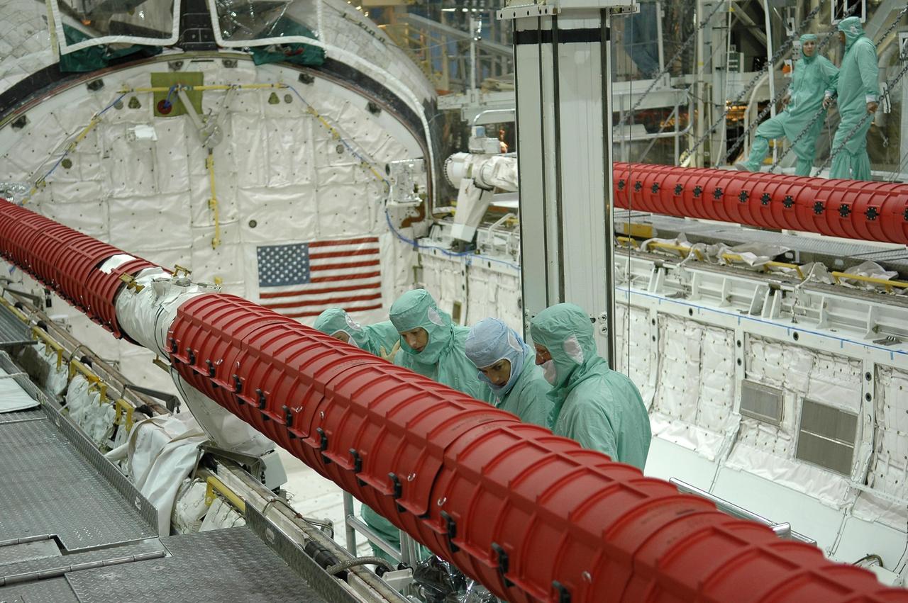 KENNEDY SPACE CENTER, FLA. -  In the Orbiter Processing Facility at NASA's Kennedy Space Center, STS-115 crew members inspect equipment in Atlantis's payload bay. Mission Specialists Heidemarie Stefanyshyn-Piper (second from right) and Joseph Tanner (right) look at the orbiter boom sensor system.  The crew is at KSC for Crew Equipment Interface Test activities, which involves equipment familiarization,  a routine part of astronaut training and launch preparations.  The STS-115 mission will deliver the second port truss segment, the P3/P4 truss, to the International Space Station.  The crew will attach the P3 to the first port truss segment, the P1 truss, as well as deploy solar array set 2A and 4A.  Launch on Space Shuttle Atlantis is scheduled for late August. Photo credit: NASA/Kim Shiflett