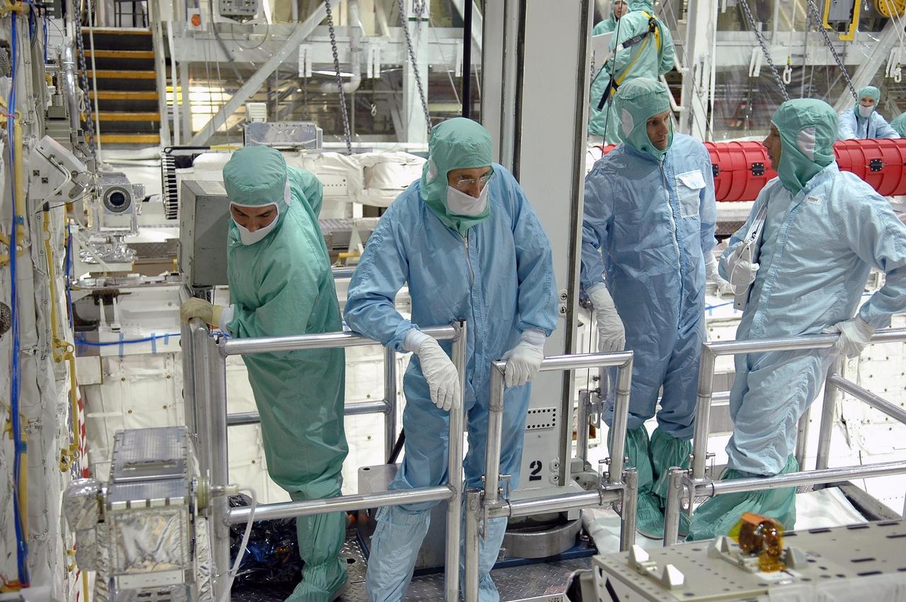KENNEDY SPACE CENTER, FLA. -  In the Orbiter Processing Facility at NASA's Kennedy Space Center, STS-115 crew members inspect equipment in Atlantis's payload bay. Mission Specialist Daniel Burbank (second from left) looks into the bay.  Next to him on the right is Mission Specialist Steven MacLean, talking to a technician.  The crew is at KSC for Crew Equipment Interface Test activities, which involves equipment familiarization,  a routine part of astronaut training and launch preparations.  The STS-115 mission will deliver the second port truss segment, the P3/P4 truss, to the International Space Station.  The crew will attach the P3 to the first port truss segment, the P1 truss, as well as deploy solar array set 2A and 4A.  Launch on Space Shuttle Atlantis is scheduled for late August. Photo credit: NASA/Kim Shiflett