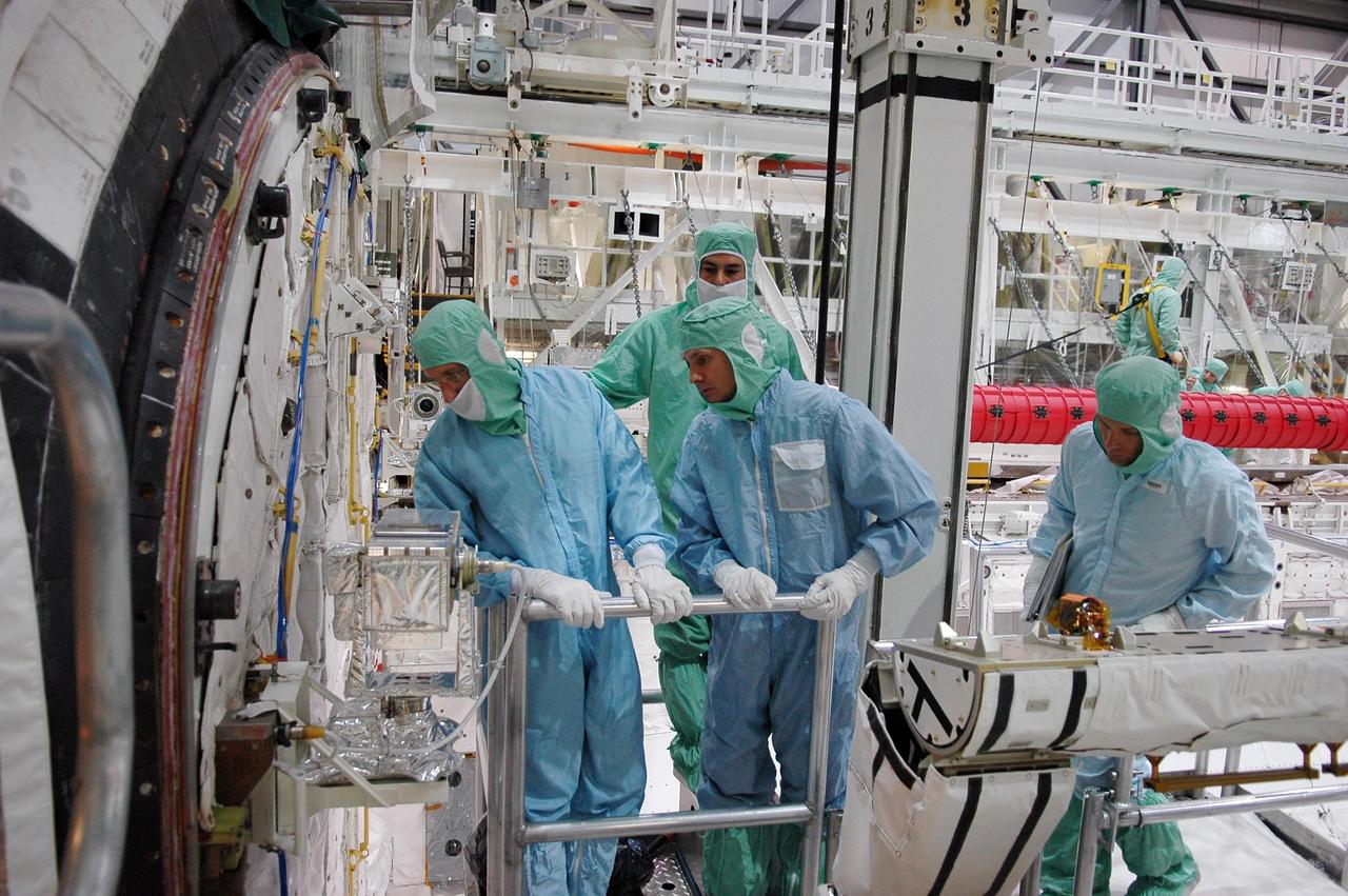 KENNEDY SPACE CENTER, FLA. -  In the Orbiter Processing Facility at NASA's Kennedy Space Center, STS-115 crew members inspect equipment in Atlantis's payload bay.  Looking at the airlock are Mission Specialist Daniel Burbank (left) and Steven MacLean.  The crew is at KSC for Crew Equipment Interface Test activities, which involves equipment familiarization,  a routine part of astronaut training and launch preparations.  The STS-115 mission will deliver the second port truss segment, the P3/P4 truss, to the International Space Station.  The crew will attach the P3 to the first port truss segment, the P1 truss, as well as deploy solar array set 2A and 4A.  Launch on Space Shuttle Atlantis is scheduled for late August. Photo credit: NASA/Kim Shiflett