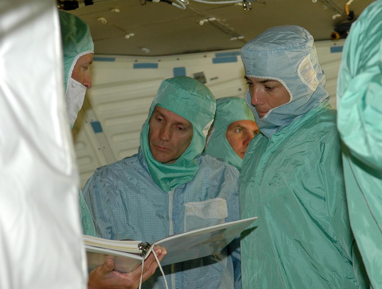 KENNEDY SPACE CENTER, FLA. -  In the Orbiter Processing Facility, STS-115 Mission Speciailsts Steven MacLean and Heidemarie Stefanyshyn-Piper (center) review procedures for launch while inspecting the orbiter Atlantis.  The crew is at KSC for Crew Equipment Interface Test activities, which involve equipment familiarization and inspection, a routine part of astronaut training and launch preparations.  The STS-115 mission will deliver the second port truss segment, the P3/P4 truss, to the International Space Station.  The crew will attach the P3 to the first port truss segment, the P1 truss, as well as deploy solar array set 2A and 4A.  Launch on Space Shuttle Atlantis is scheduled for late August. Photo credit: NASA/Kim Shiflett
