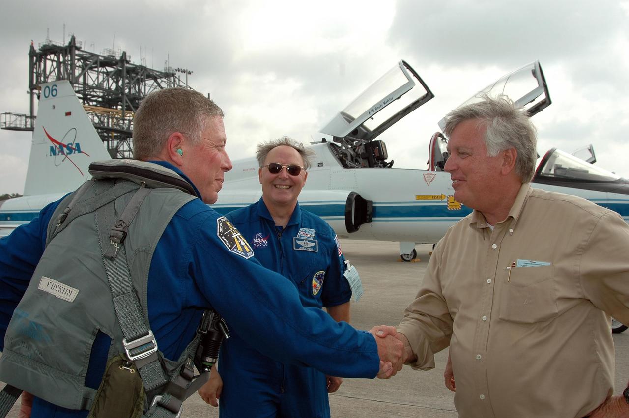 KENNEDY SPACE CENTER, FLA. - STS-121 Mission Specialist Michael Fossum (left) is greeted by Center Director Jim Kennedy after arriving at KSC to get ready for launch on July 1. Behind him is Jerry Ross, who is chief of the Vehicle Integration Test Office at Johnson Space Center. During the 12-day mission, the STS-121 crew will test new equipment and procedures to improve shuttle safety, as well as deliver supplies and make repairs to the International Space Station. This mission is the 115th shuttle flight and the 18th U.S. flight to the International Space Station. Photo credit: NASA/Kim Shiflett