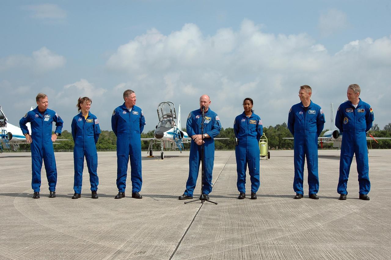 KENNEDY SPACE CENTER, FLA. - After their arrival at KSC to prepare for launch on July 1, the STS-121 crew greets the media on the Shuttle Landing Facility. At the microphone is Pilot Mark Kelly. From left are Commander Steven Lindsey, Mission Specialists Lisa Nowak and Michael Fossum, Kelly, and Mission Specialists Stephanie Wilson, Piers Sellers and Thomas Reiter. During the 12-day mission, the STS-121 crew will test new equipment and procedures to improve shuttle safety, as well as deliver supplies and make repairs to the International Space Station. This mission is the 115th shuttle flight and the 18th U.S. flight to the International Space Station. Photo credit: NASA/Kim Shiflett