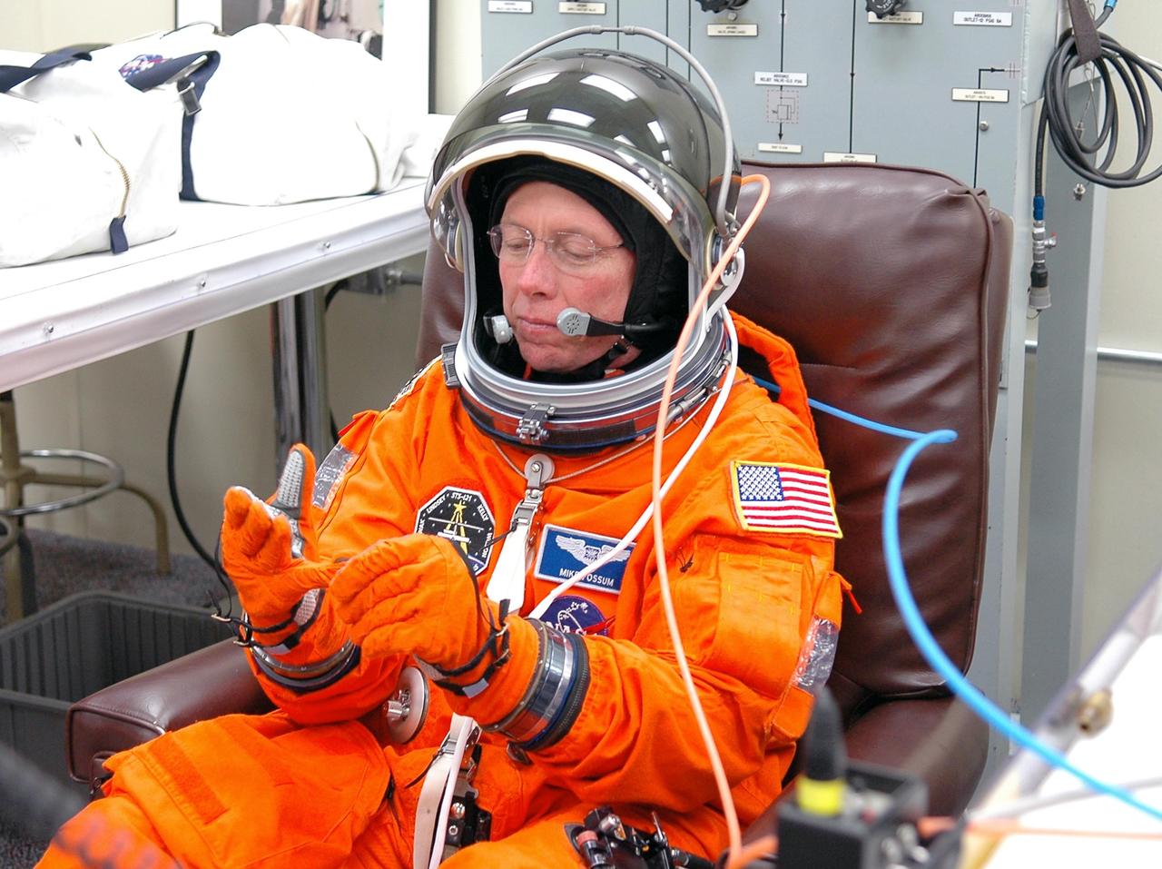 KENNEDY SPACE CENTER, FLA. - STS-121 Mission Specialist Michael Fossum finishes putting on a glove during a fitting on his launch suit in the Operations and Checkout Building. On the 12-day mission, the crew will test new equipment and procedures to improve shuttle safety, as well as deliver supplies and make repairs to the station. This mission is the 115th shuttle flight and the 18th U.S. flight to the station. Photo credit: NASA/Kim Shiflett