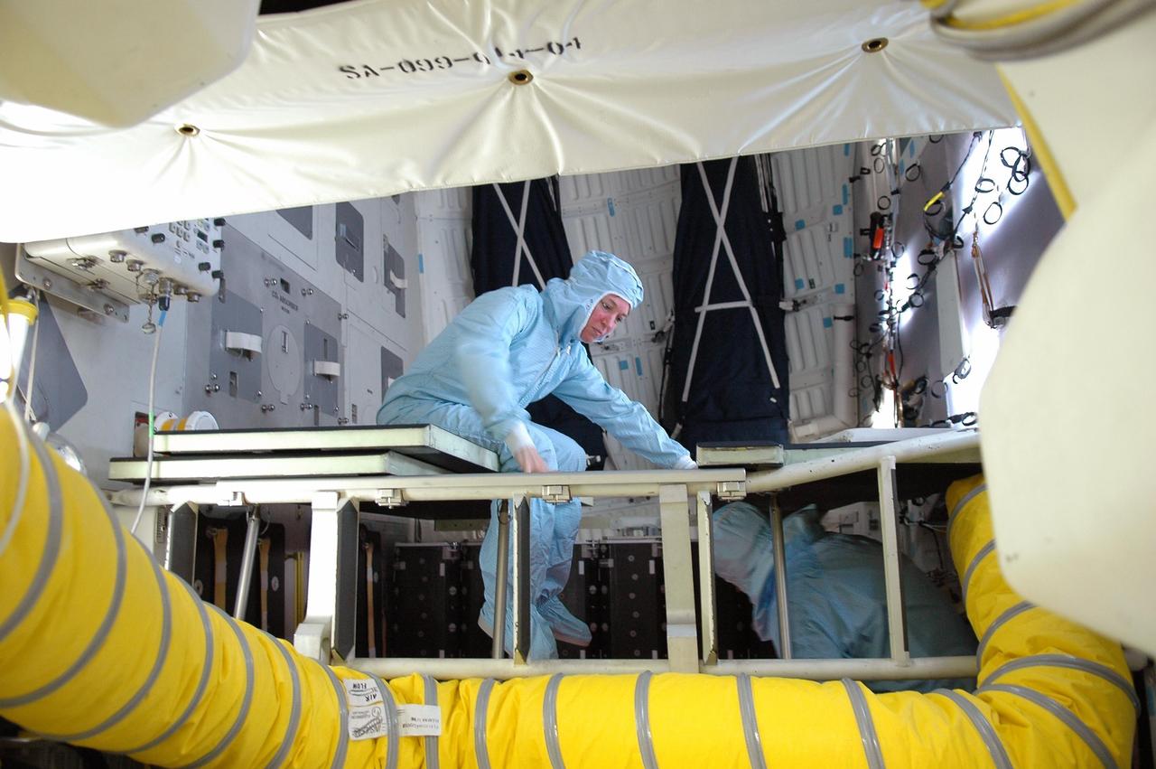 KENNEDY SPACE CENTER, FLA. - STS-121 Mission Specialists Lisa Nowak (left, above) and Piers Sellers (right, below) inspect cables in the mid-body of Space Shuttle Discovery on Launch Pad 39B. On the 12-day mission, the crew will test new equipment and procedures to improve shuttle safety, as well as deliver supplies and make repairs to the station. This mission is the 115th shuttle flight and the 18th U.S. flight to the station. Photo credit: NASA/Kim Shiflet