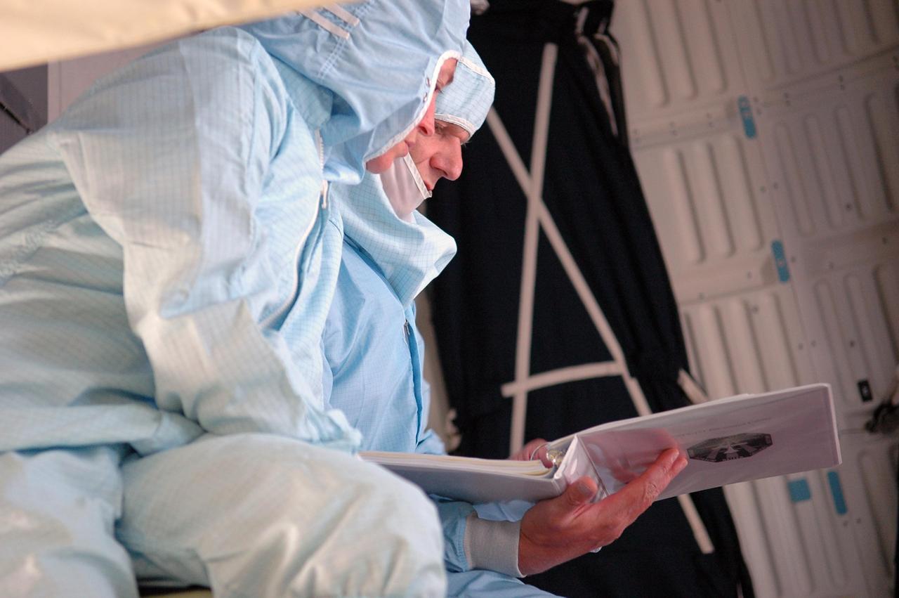 KENNEDY SPACE CENTER, FLA. - STS-121 Mission Specialists Lisa Nowak and Piers Sellers review procedures during cable inspection in the mid-body of Space Shuttle Discovery on Launch Pad 39B. On the 12-day mission, the crew will test new equipment and procedures to improve shuttle safety, as well as deliver supplies and make repairs to the station. This mission is the 115th shuttle flight and the 18th U.S. flight to the station. Photo credit: NASA/Kim Shiflet