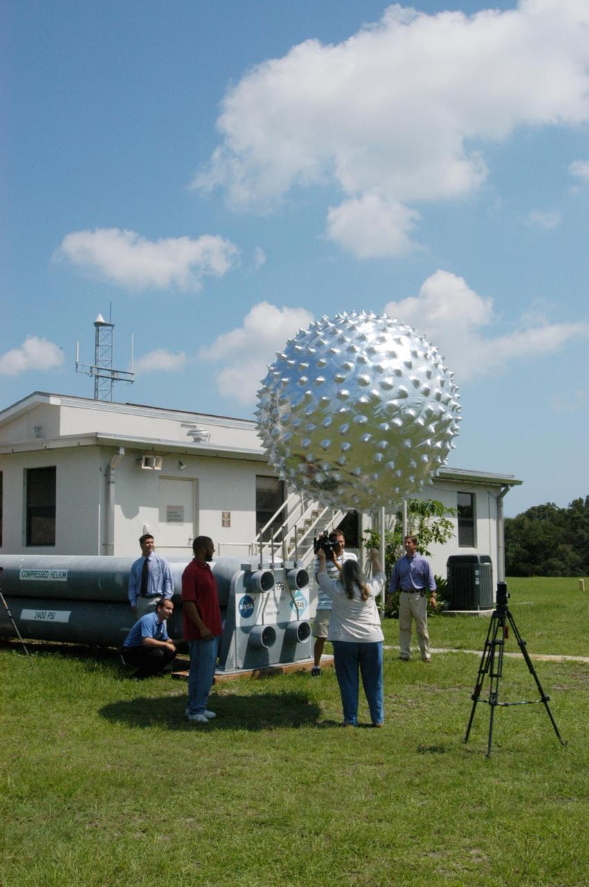 KENNEDY SPACE CENTER, FLA. -   At the Cape Canaveral weather station in Florida, workers release an upper-level weather balloon while several newscasters watch.  The release of the balloon was part of a media tour prior to the launch of Space Shuttle Discovery on mission STS-121 July 1. The radar-tracked balloon detects wind shears that can affect a shuttle launch.  At the facility, which is operated by the U.S. Air Force 45th Weather Squadron, media saw the tools used by the weather team to create the forecast for launch day. They received a briefing on how the launch weather forecast is developed by Shuttle Weather Officer Kathy Winters and met the forecasters for the space shuttle and the expendable launch vehicles. Also participating were members of the Applied Meteorology Unit who provide special expertise to the forecasters by analyzing and interpreting unusual or inconsistent weather data. The media were able to see the release of the Rawinsonde weather balloon carrying instruments aloft to be used as part of developing the forecast.  Photo credit: NASA/George Shelton