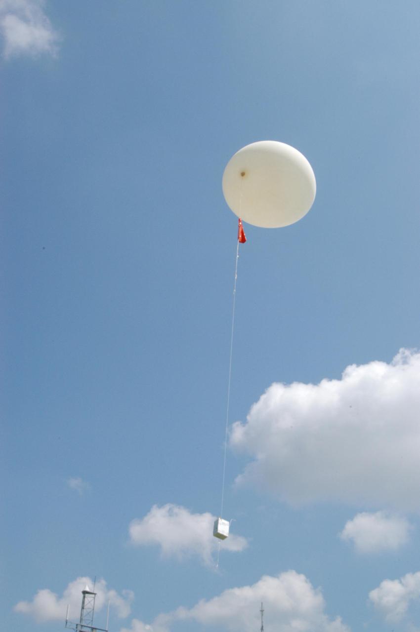KENNEDY SPACE CENTER, FLA. -   A Rawinsonde weather balloon sails into the sky after  release from the Cape Canaveral forecast facility in Florida.  The release was planned as part of a media tour prior to the launch of Space Shuttle Discovery on mission STS-121 July 1. Rawinsonde balloons are GPS-tracked and can collect such data as atmospheric pressure, temperature, humidity and wind speed and direction up to 100,000 feet.  At the facility, which is operated by the U.S. Air Force 45th Weather Squadron, media saw the tools used by the weather team to create the forecast for launch day. They received a briefing on how the launch weather forecast is developed by Shuttle Weather Officer Kathy Winters and met the forecasters for the space shuttle and the expendable launch vehicles. Also participating were members of the Applied Meteorology Unit who provide special expertise to the forecasters by analyzing and interpreting unusual or inconsistent weather data. The media were able to see the release of the Rawinsonde weather balloon carrying instruments aloft to be used as part of developing the forecast.  Photo credit: NASA/George Shelton