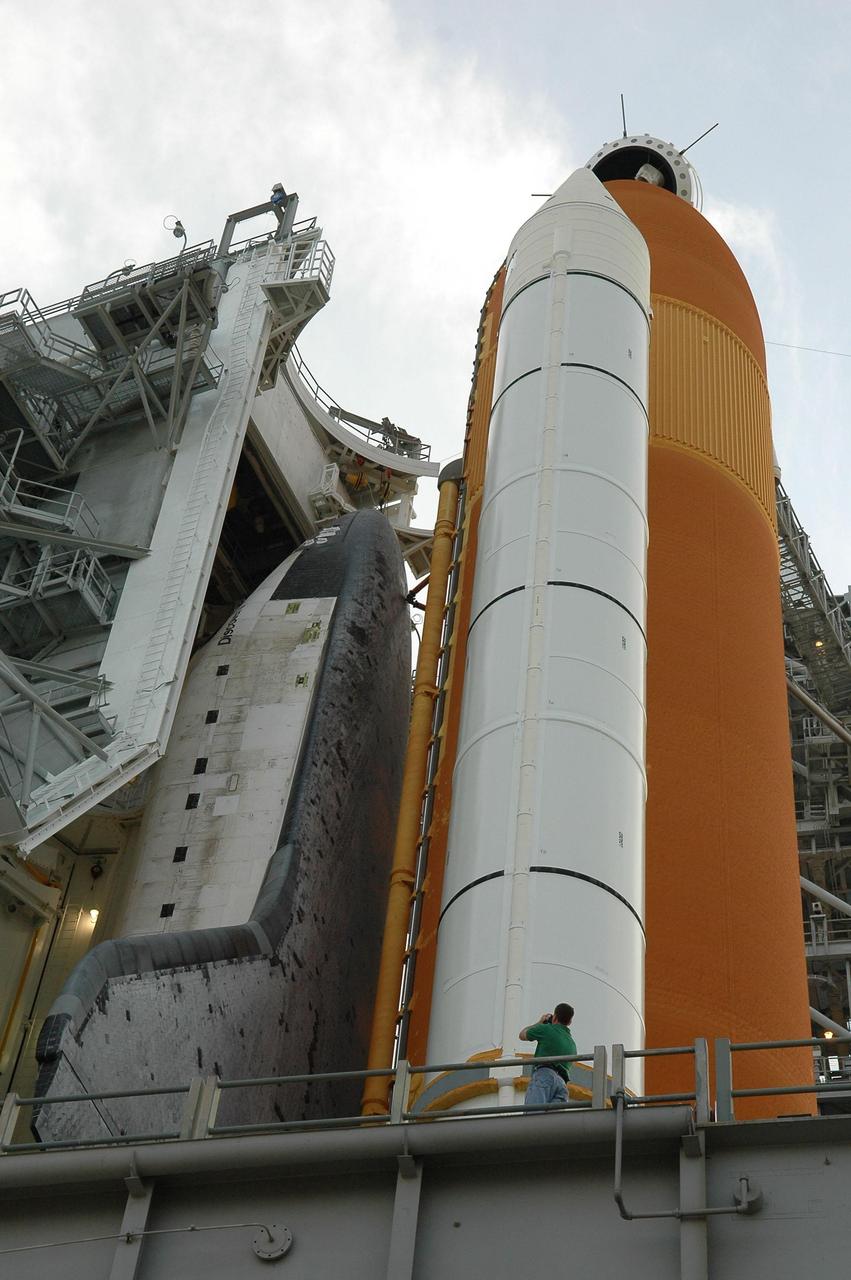 KENNEDY SPACE CENTER, FLA. -   In preparation for the July 1 launch of Space Shuttle Discovery on mission STS-121, the Launch Pad 39B rotating service structure (RSS) enclosing the shuttle begins to roll away as light starts to fade from the sky.  Above the golden external tank is the vent hood (known as the "beanie cap") at the end of the gaseous oxygen vent arm. Vapors are created as the liquid oxygen in the external tank boil off. The hood vents the gaseous oxygen vapors away from the space shuttle vehicle. The RSS provides protected access to the orbiter for changeout and servicing of payloads at the pad. The structure is supported by a rotating bridge that pivots about a vertical axis on the west side of the pad's flame trench. The hinge column rests on the pad surface and is braced to the fixed service structure. Support for the outer end of the bridge is provided by two eight-wheel, motor-driven trucks that move along circular twin rails installed flush with the pad surface. The track crosses the flame trench on a permanent bridge.  The RSS is 102 feet long, 50 feet wide and 130 feet high. The structure has orbiter access platforms at five levels to provide access to the payload bay while the orbiter is being serviced in the RSS. Each platform has independent extendable planks that can be arranged to conform to a payload's configuration.  This mission is the 115th shuttle flight and the 18th U.S. flight to the International Space Station. Photo credit: NASA/Kim Shiflett