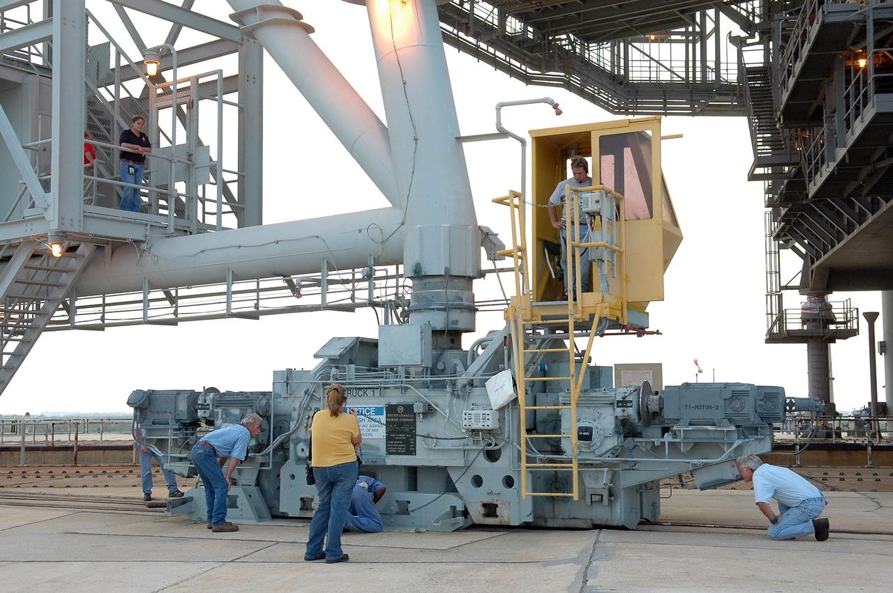 KENNEDY SPACE CENTER, FLA. -   On Launch Pad 39B, workers check one of the two trucks that move the rotating service structure (RSS).  In preparation for the July 1 launch of Space Shuttle Discovery on mission STS-121, the RSS is being rolled away from the shuttle.  The RSS provides protected access to the orbiter for changeout and servicing of payloads at the pad. The structure is supported by a rotating bridge that pivots about a vertical axis on the west side of the pad's flame trench. The hinge column rests on the pad surface and is braced to the fixed service structure. Support for the outer end of the bridge is provided by two eight-wheel, motor-driven trucks that move along circular twin rails installed flush with the pad surface. The track crosses the flame trench on a permanent bridge.  The RSS is 102 feet long, 50 feet wide and 130 feet high. The structure has orbiter access platforms at five levels to provide access to the payload bay while the orbiter is being serviced in the RSS. Each platform has independent extendable planks that can be arranged to conform to a payload's configuration.  This mission is the 115th shuttle flight and the 18th U.S. flight to the International Space Station. Photo credit: NASA/Kim Shiflett