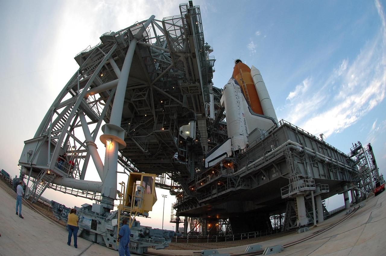 KENNEDY SPACE CENTER, FLA. -   A fish-eye camera lens captures the movement of the rotating service structure (RSS) at left as it moves away from Space Shuttle Discovery in  preparation for the July 1 launch from Launch Pad 39B. The RSS provides protected access to the orbiter for changeout and servicing of payloads at the pad. The structure is supported by a rotating bridge that pivots about a vertical axis on the west side of the pad's flame trench. The hinge column rests on the pad surface and is braced to the fixed service structure. Support for the outer end of the bridge is provided by two eight-wheel, motor-driven trucks that move along circular twin rails installed flush with the pad surface. The track crosses the flame trench on a permanent bridge.  The RSS is 102 feet long, 50 feet wide and 130 feet high. The structure has orbiter access platforms at five levels to provide access to the payload bay while the orbiter is being serviced in the RSS. Each platform has independent extendable planks that can be arranged to conform to a payload's configuration.  This mission is the 115th shuttle flight and the 18th U.S. flight to the International Space Station. Photo credit: NASA/Kim Shiflett