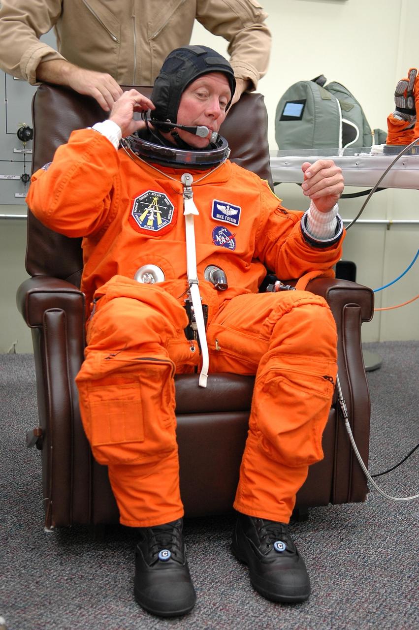 KENNEDY SPACE CENTER, FLA. -   STS-121 Mission Specialist Michael Fossum is helped with the communication device he wears under his helmet during suitup for launch today on Space Shuttle Discovery. The launch is the 115th shuttle flight and the 18th U.S. flight to the International Space Station.  During the 12-day mission, the STS-121 crew will test new equipment and procedures to improve shuttle safety, as well as deliver supplies and make repairs to the International Space Station.  Photo credit: NASA/Kim Shiflett