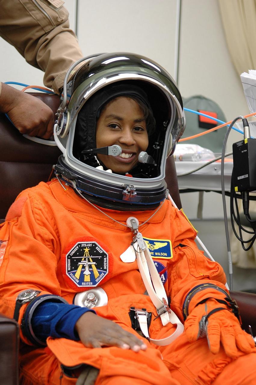 KENNEDY SPACE CENTER, FLA. -  STS-121  Mission Specialist Stephanie Wilson is helped with her helmet during suitup for launch today on Space Shuttle Discovery.   The launch is the 115th shuttle flight and the 18th U.S. flight to the International Space Station.  During the 12-day mission, the STS-121 crew will test new equipment and procedures to improve shuttle safety, as well as deliver supplies and make repairs to the International Space Station.  Photo credit: NASA/Kim Shiflett