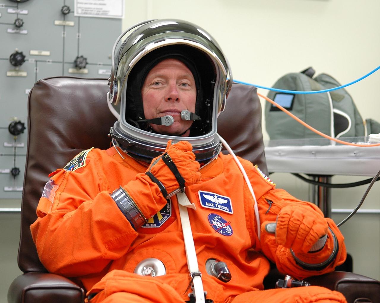 KENNEDY SPACE CENTER, FLA. -     The STS-121 crew are donning their orange launch and entry suits for launch today on Space Shuttle Discovery.  Adjusting his helmet is Mission Specialist Michael Fossum, who is making his first space flight.  The launch is the 115th shuttle flight and the 18th U.S. flight to the International Space Station.  During the 12-day mission, the STS-121 crew will test new equipment and procedures to improve shuttle safety, as well as deliver supplies and make repairs to the International Space Station.  Photo credit: NASA/Kim Shiflett