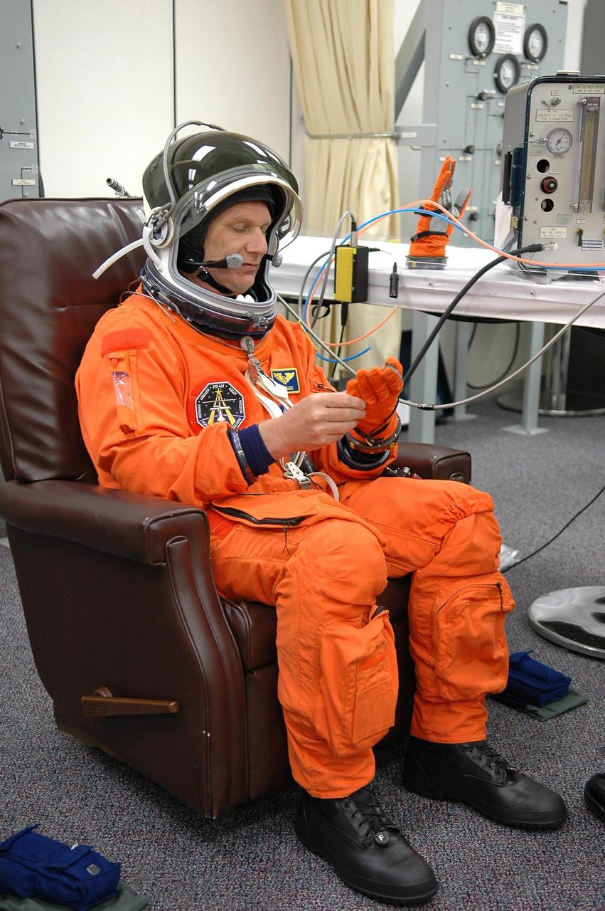 KENNEDY SPACE CENTER, FLA. -     The STS-121 crew are donning their orange launch and entry suits for launch today on Space Shuttle Discovery.  Here, Mission Specialist Piers Sellers adjusts his glove.  Sellers is making his second space flight.  The launch is the 115th shuttle flight and the 18th U.S. flight to the International Space Station.  During the 12-day mission, the STS-121 crew will test new equipment and procedures to improve shuttle safety, as well as deliver supplies and make repairs to the International Space Station.  Photo credit: NASA/Kim Shiflett
