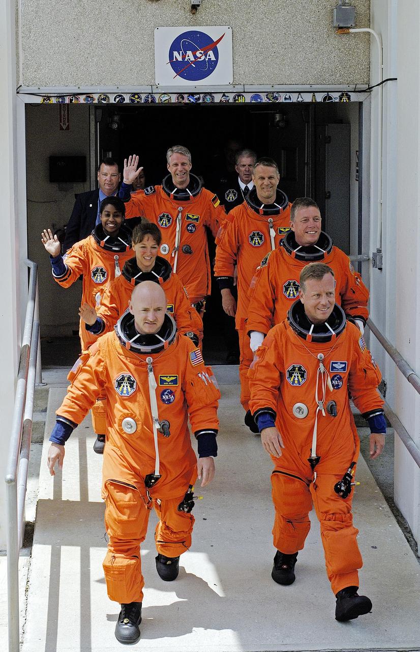 KENNEDY SPACE CENTER, FLA. - The STS-121 crew strides out of the Operations and Checkout Building after suiting up for launch today on Space Shuttle Discovery. On the left column from back to front are Mission Specialists Thomas Reiter, Stephanie Wilson and Lisa Nowak, and Pilot Mark Kelly. On the right column from back to front are Mission Specialists Piers Sellers and Michael Fossum, with Commander Steven Lindsey leading the way. The launch is the 115th shuttle flight and the 18th U.S. flight to the International Space Station. During the 12-day mission, the STS-121 crew will test new equipment and procedures to improve shuttle safety, as well as deliver supplies and make repairs to the International Space Station. Photo courtesy of Nikon/Scott Andrews