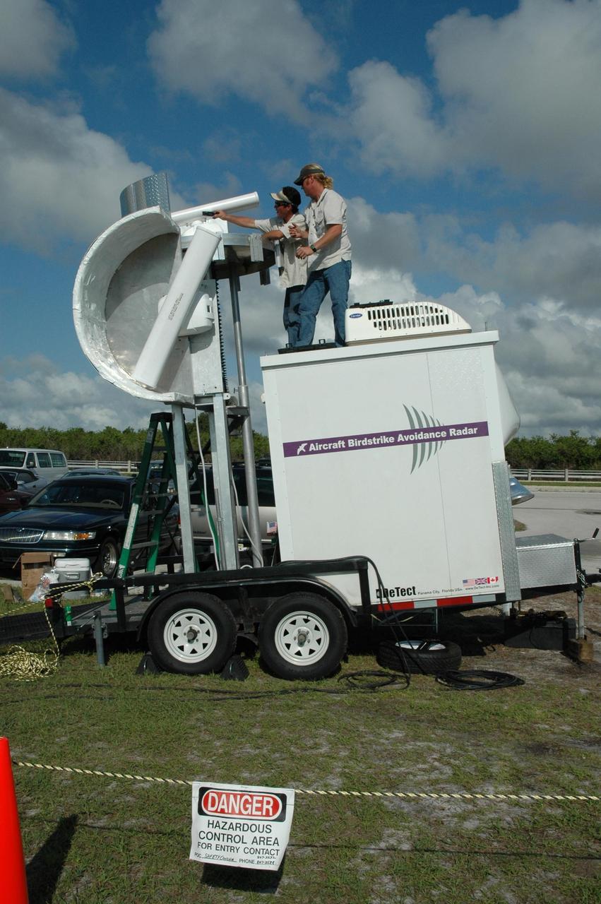KENNEDY SPACE CENTER, FLA. - Radar technicians adjust two bird detection radars near Launch Pad 39B before the July 1 launch of Space Shuttle Discovery on mission STS-121. When birds, especially vultures, are near the shuttle during a launch, impact on a critical area is possible and could cause catastrophic damage to the vehicle. Already proven affective for aviation where threats posed by bird strikes have been a problem, the avian radar, known as Aircraft Birdstrike Avoidance Radar, provides horizontal and vertical scanning and can monitor either launch pad for movement of vultures around them. If data relayed from the avian radar indicates large birds are dangerously close to the vehicle, controllers could hold the countdown. Photo credit: NASA/Dimitri Gerondidakis