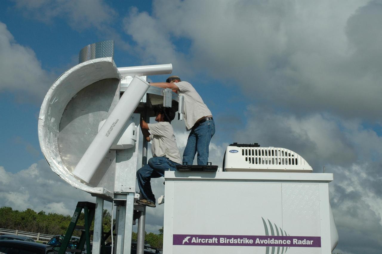 KENNEDY SPACE CENTER, FLA. - Radar technicians adjust two bird detection radars near Launch Pad 39B before the July 1 launch of Space Shuttle Discovery on mission STS-121. When birds, especially vultures, are near the shuttle during a launch, impact on a critical area is possible and could cause catastrophic damage to the vehicle. Already proven affective for aviation where threats posed by bird strikes have been a problem, the avian radar, known as Aircraft Birdstrike Avoidance Radar, provides horizontal and vertical scanning and can monitor either launch pad for movement of vultures around them. If data relayed from the avian radar indicates large birds are dangerously close to the vehicle, controllers could hold the countdown. Photo credit: NASA/Dimitri Gerondidakis