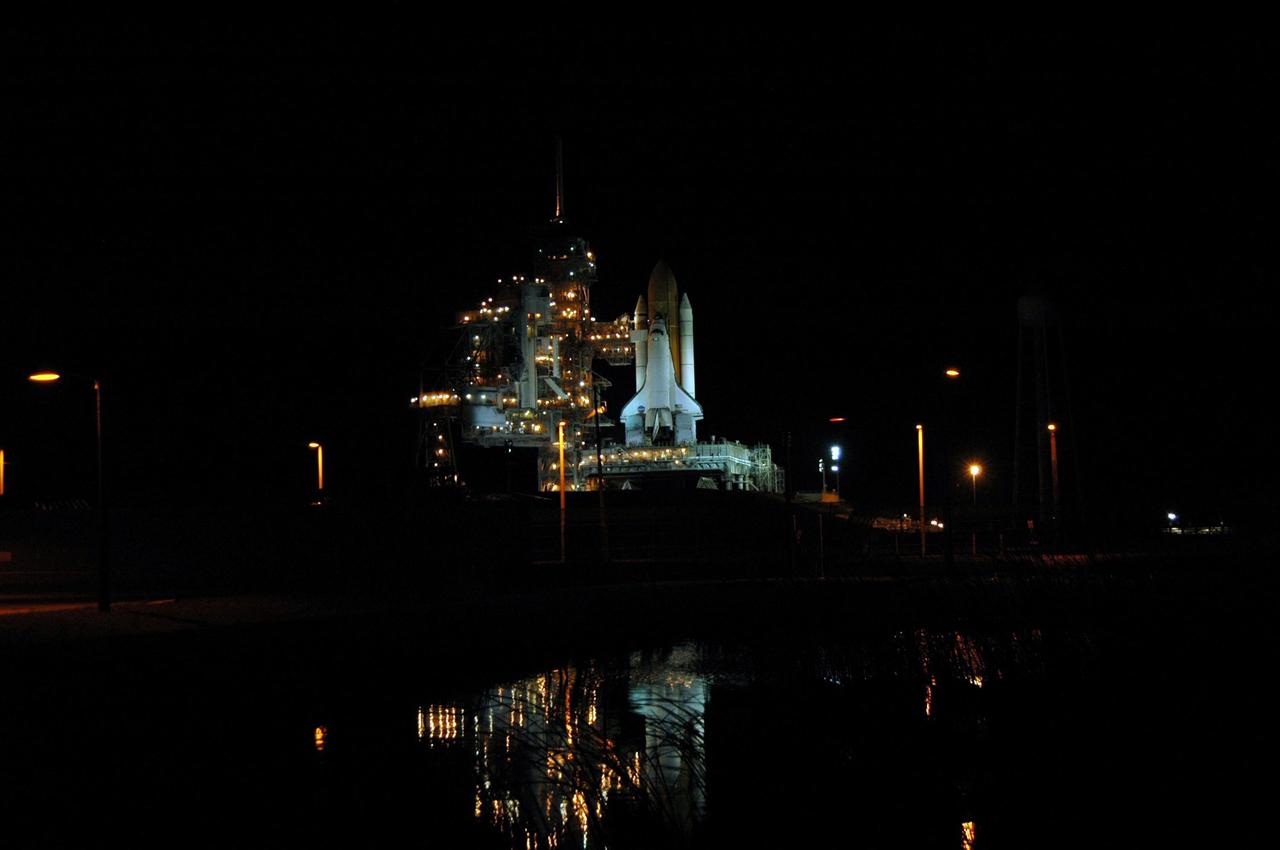 KENNEDY SPACE CENTER, FLA. -    Viewed from across the pond next to Launch Pad 39B, Space Shuttle Discovery is spotlighted under dark skies after the scrub of the launch attempt on mission STS-121.  The launch was scrubbed due to weather concerns and postponed 24 hours.  Photo credit: NASA/Ken Thornsley