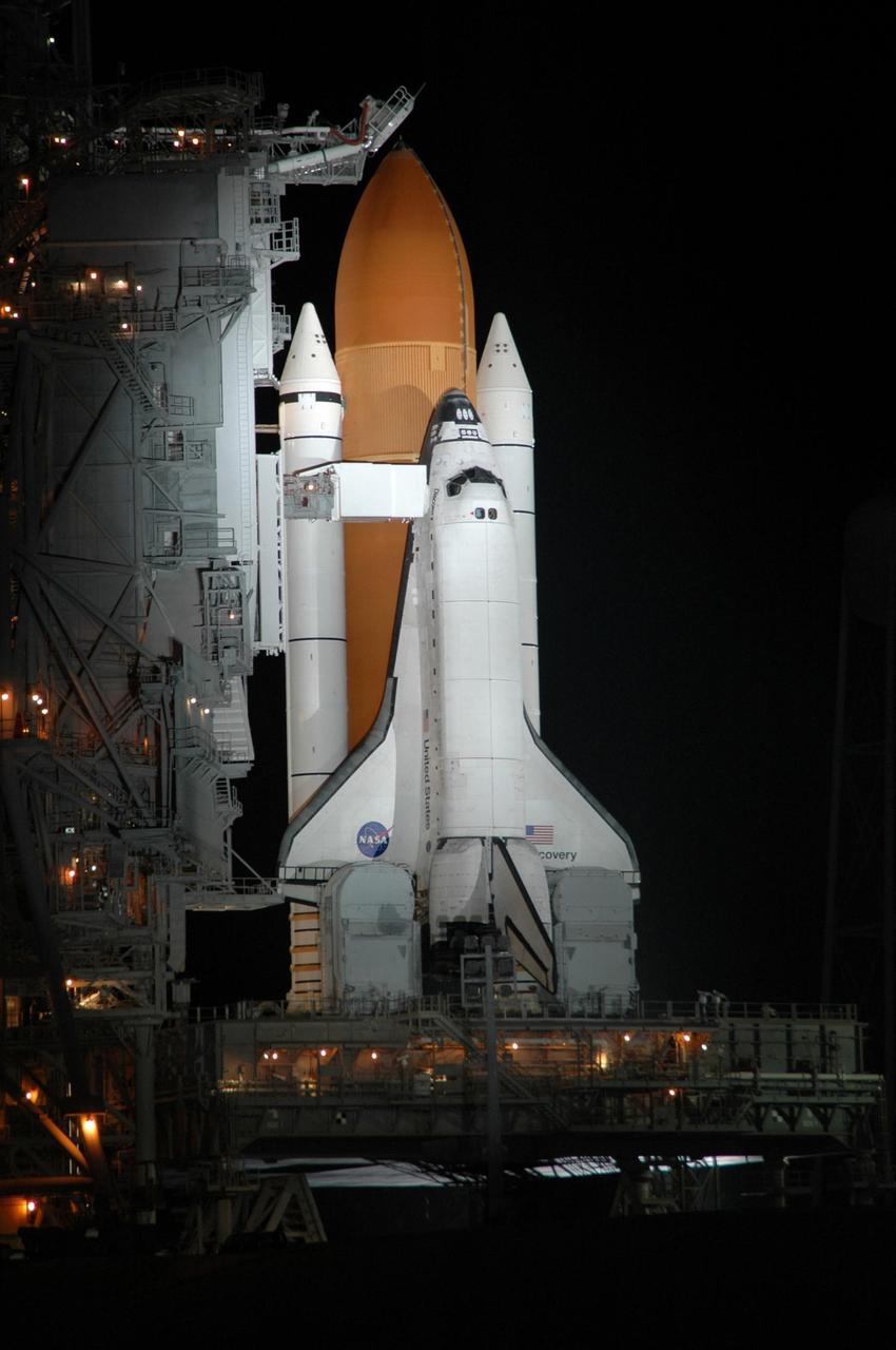 KENNEDY SPACE CENTER, FLA. -    On Launch Pad 39B, Space Shuttle Discovery is bathed in spotlights under dark skies after the scrub of the launch attempt on mission STS-121.  The White Room extends toward the cockpit area where the STS-121 crew patiently waited for the launch just hours earlier.  The launch was scrubbed due to weather concerns and postponed 24 hours.  Photo credit: NASA/Ken Thornsley