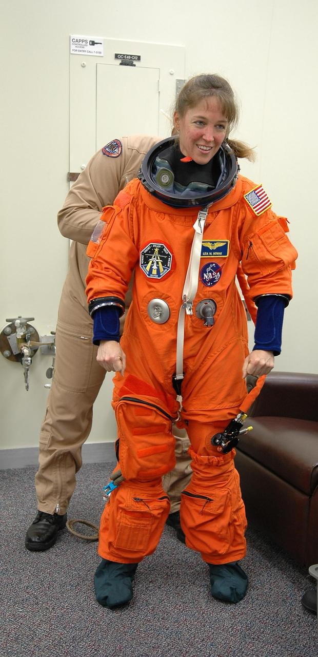 KENNEDY SPACE CENTER, FLA. -  STS-121 Mission Specialist Lisa Nowak gets help with her launch suit for a second launch attempt on Space Shuttle Discovery.  The first launch attempt July 1 was scrubbed due to weather concerns and postponed 24 hours.  The launch is the 115th shuttle flight and the 18th U.S. flight to the International Space Station.  During the 12-day mission, the STS-121 crew will test new equipment and procedures to improve shuttle safety, as well as deliver supplies and make repairs to the International Space Station. Photo credit: NASA/Kim Shiflett