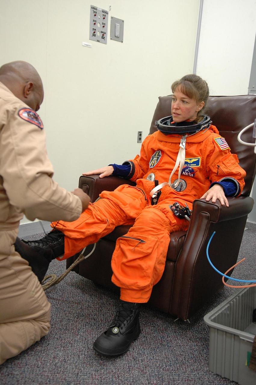 KENNEDY SPACE CENTER, FLA. -   STS-121 Mission Specialist Lisa Nowak is helped with her boot during suitup  for a second launch attempt on Space Shuttle Discovery.  The first launch attempt July 1 was scrubbed due to weather concerns and postponed 24 hours. The launch of Space Shuttle Discovery on mission STS-121 is the 115th shuttle flight and the 18th U.S. flight to the International Space Station.  During the 12-day mission, the STS-121 crew will test new equipment and procedures to improve shuttle safety, as well as deliver supplies and make repairs to the International Space Station.  Photo credit: NASA/Kim Shiflett