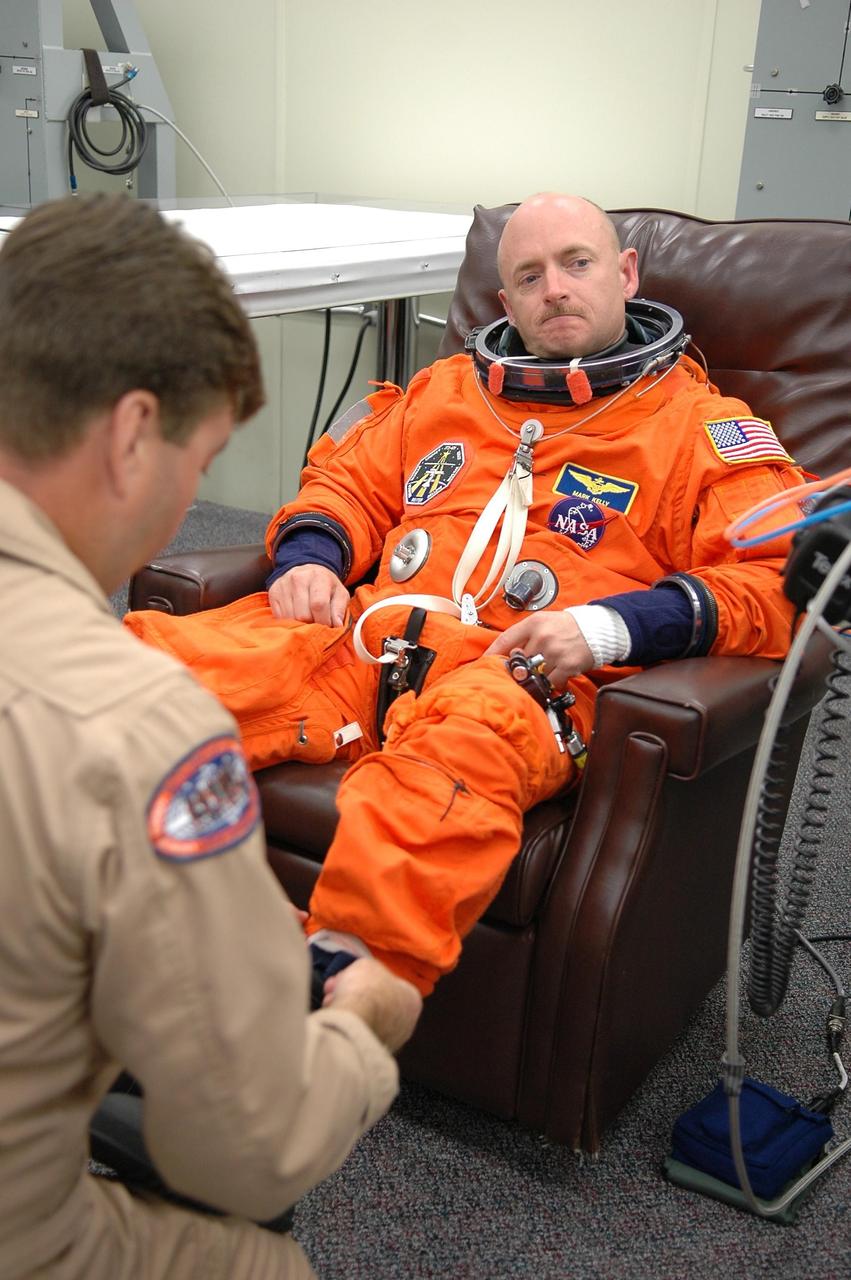 KENNEDY SPACE CENTER, FLA. -   STS-121 Pilot Mark Kelly is helped with his boot during suitup for a second launch attempt on Space Shuttle Discovery.  The first launch attempt July 1 was scrubbed due to weather concerns and postponed 24 hours. The launch of Space Shuttle Discovery on mission STS-121 is the 115th shuttle flight and the 18th U.S. flight to the International Space Station.  During the 12-day mission, the STS-121 crew will test new equipment and procedures to improve shuttle safety, as well as deliver supplies and make repairs to the International Space Station.  Photo credit: NASA/Kim Shiflett