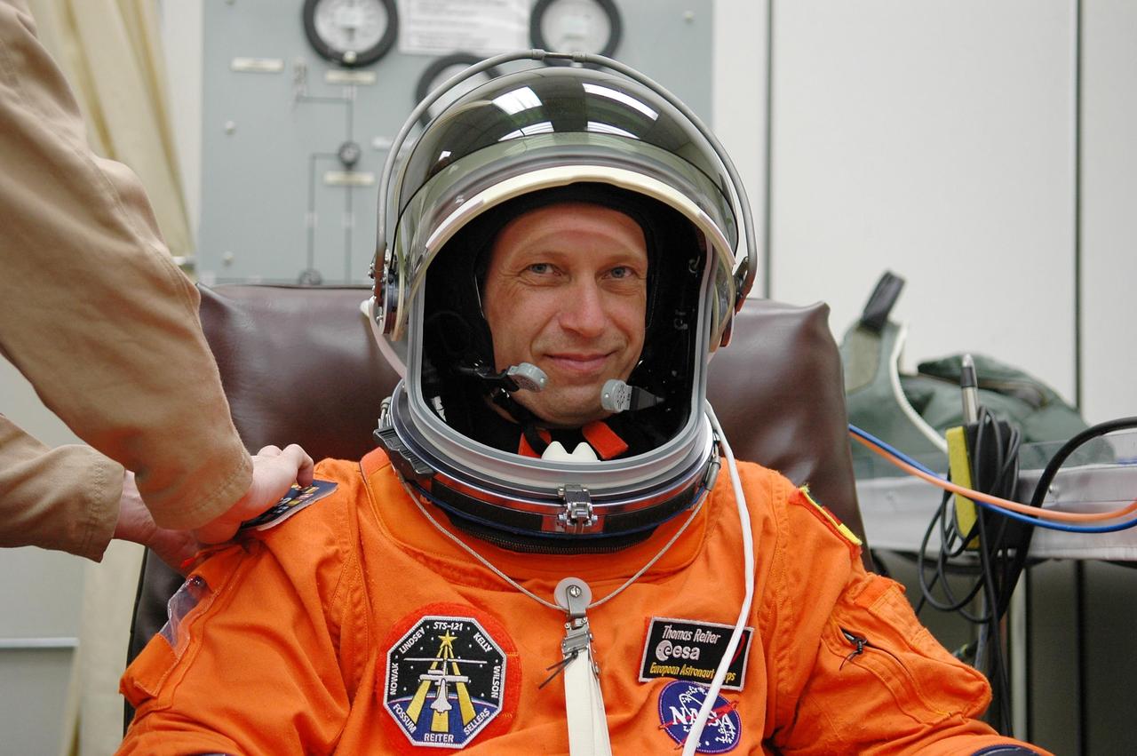 KENNEDY SPACE CENTER, FLA. -   Prior to the third launch attempt on mission STS-121, Mission Specialist Thomas Reiter is helped with his helmet during suitup before heading to Launch Pad 39B.  The July 2 launch attempt was scrubbed due to the presence of showers and thunderstorms within the surrounding area of the launch site. The launch of Space Shuttle Discovery on mission STS-121 is the 115th shuttle flight and the 18th U.S. flight to the International Space Station.  During the 12-day mission, the STS-121 crew will test new equipment and procedures to improve shuttle safety, as well as deliver supplies and make repairs to the International Space Station.  Photo credit: NASA/Kim Shiflett