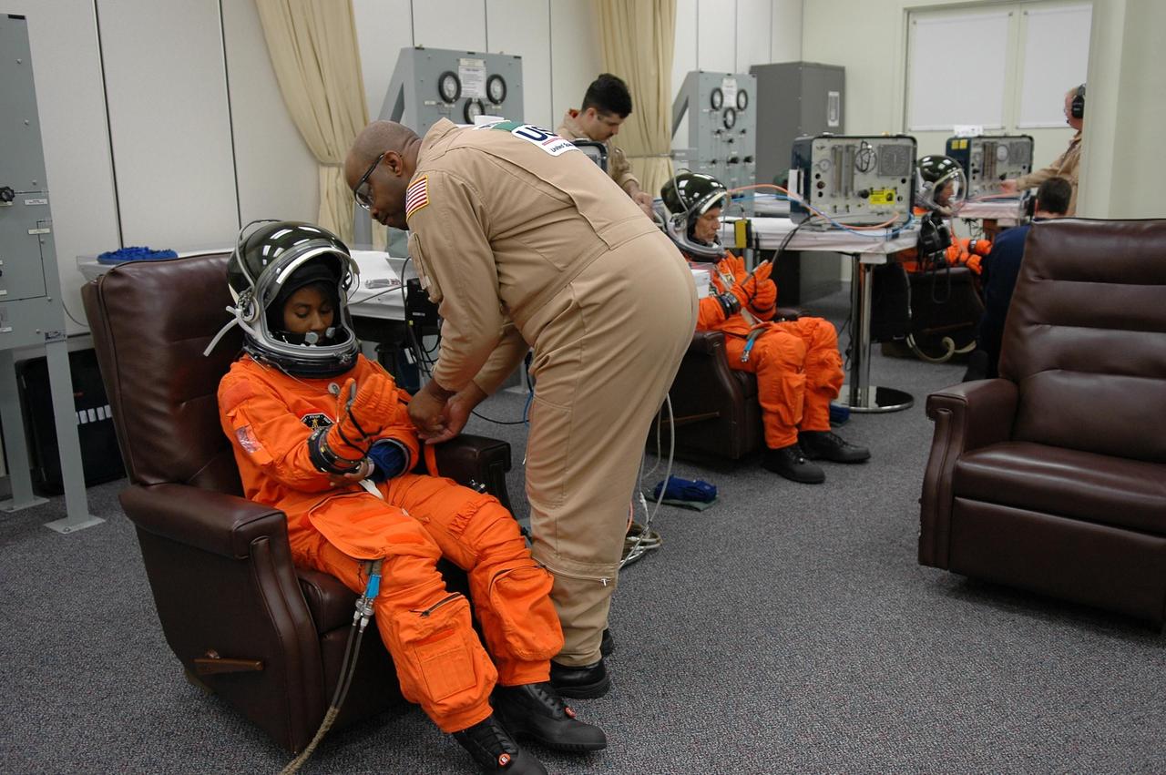 KENNEDY SPACE CENTER, FLA. -   Prior to the third launch attempt on mission STS-121, Mission Specialist Stephanie Wilson pulls on her gloves while getting help with her launch suit before heading to Launch Pad 39B.  The launch of Space Shuttle Discovery on mission STS-121 is the 115th shuttle flight and the 18th U.S. flight to the International Space Station.  During the 12-day mission, the STS-121 crew will test new equipment and procedures to improve shuttle safety, as well as deliver supplies and make repairs to the International Space Station.  Photo credit: NASA/Kim Shiflett