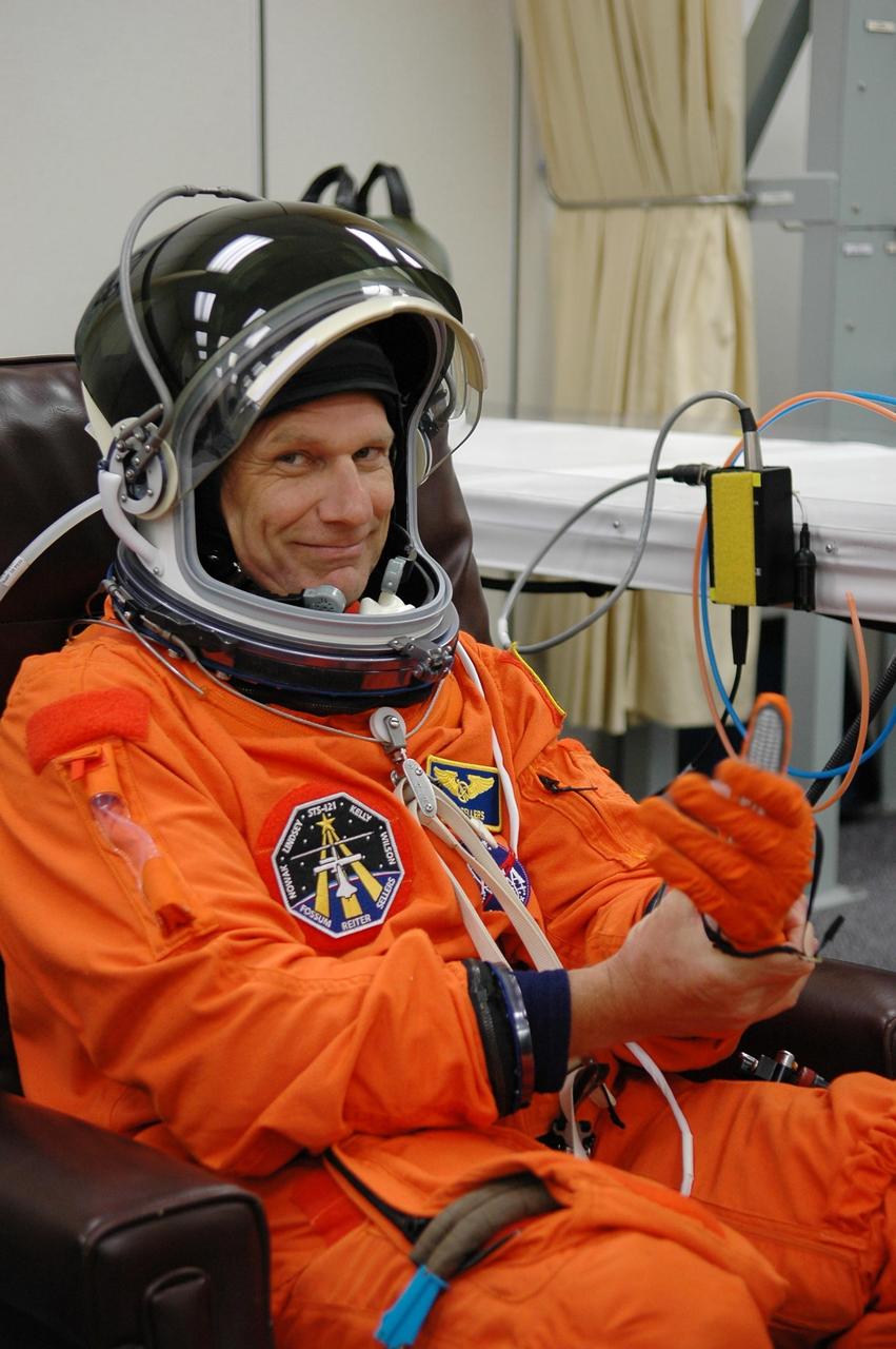 KENNEDY SPACE CENTER, FLA. - Mission Specialist Piers Sellers is happy to be making a third launch attempt on mission STS-121. Here, he fixes one of his gloves during suitup before heading to Launch Pad 39B. The July 2 launch attempt was scrubbed due to the presence of showers and thunderstorms within the surrounding area of the launch site. The launch of Space Shuttle Discovery on mission STS-121 is the 115th shuttle flight and the 18th U.S. flight to the International Space Station. During the 12-day mission, the STS-121 crew will test new equipment and procedures to improve shuttle safety, as well as deliver supplies and make repairs to the International Space Station. Photo credit: NASA/Kim Shiflett
