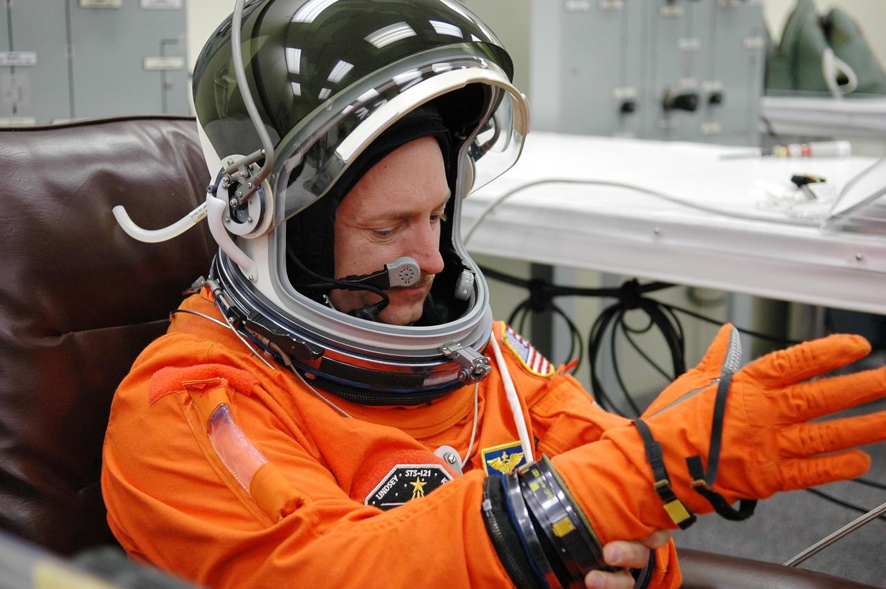 KENNEDY SPACE CENTER, FLA. - Prior to the third launch attempt on mission STS-121, Pilot Mark Kelly fixes his glove during suitup before heading to Launch Pad 39B. The July 2 launch attempt was scrubbed due to the presence of showers and thunderstorms within the surrounding area of the launch site. The launch of Space Shuttle Discovery on mission STS-121 is the 115th shuttle flight and the 18th U.S. flight to the International Space Station. During the 12-day mission, the STS-121 crew will test new equipment and procedures to improve shuttle safety, as well as deliver supplies and make repairs to the International Space Station. Photo credit: NASA/Kim Shiflett
