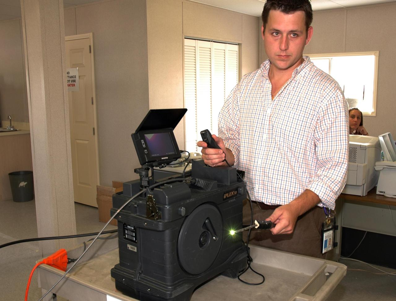 KENNEDY SPACE CENTER, FLA. -  In the Press Site at NASA's Kennedy Space Center, Charles Wassen, with the United Space Alliance Micro Inspection Team, demonstrates the boroscope camera probe, with the light glowing, that was used to verify the condition of the foam on Space Shuttle Discovery's external tank.   On July 2, a crack formed on a piece of insulation on a strut that attaches the liquid oxygen feedline to External Tank-119, being used to launch space shuttle mission STS-121. It was recovered by the Ice Team from the mobile launch platform at Pad 39B. The camera was used to get a closeup of the area for the mission management team to examine and evaluate if the launch attempt should proceed on July 4.  Photo credit: NASA/Carl Winebarger